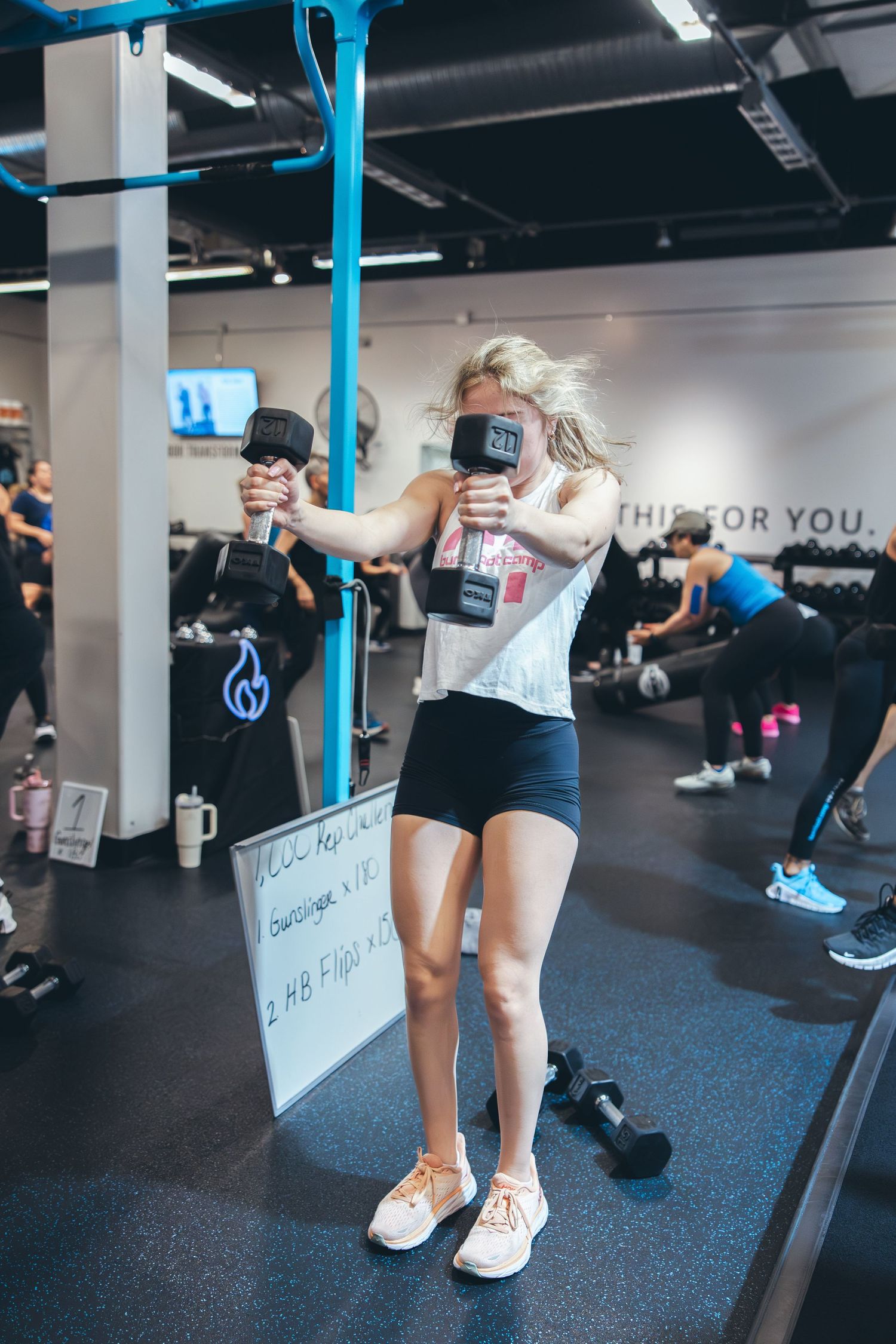 Participant performs a dynamic exercise with gym equipment in a modern fitness facility.