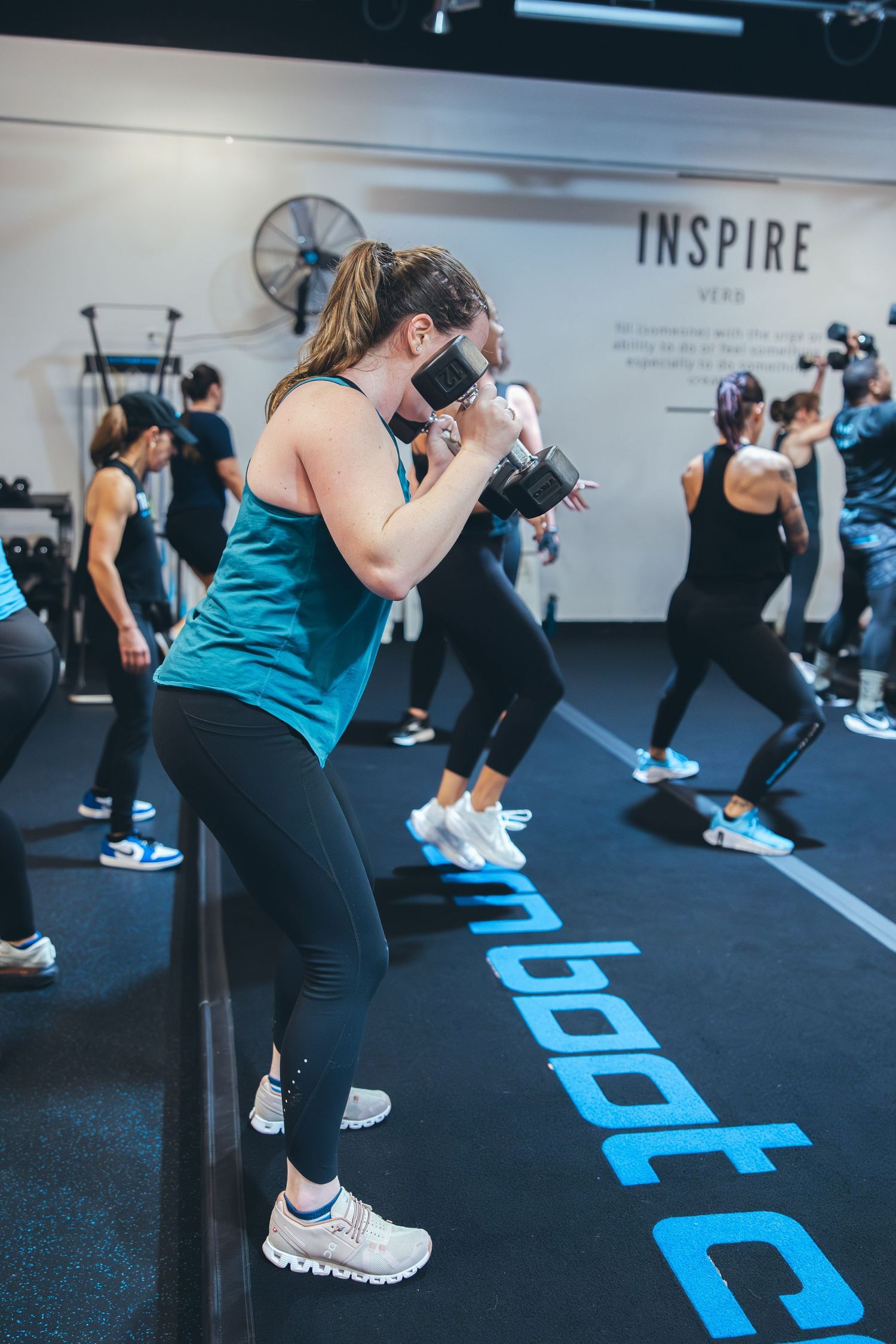 Woman in teal tank top throwing boxing punches during a fitness class at Burn Boot Camp.