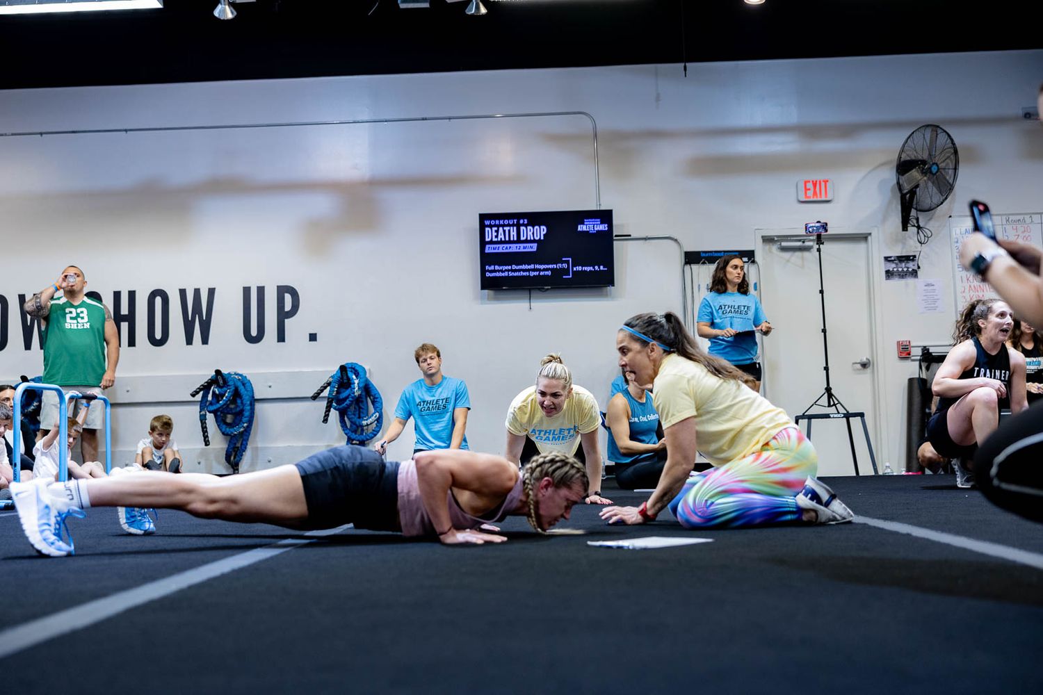 Fitness enthusiasts engage in floor exercises during a group workout session in a gym.