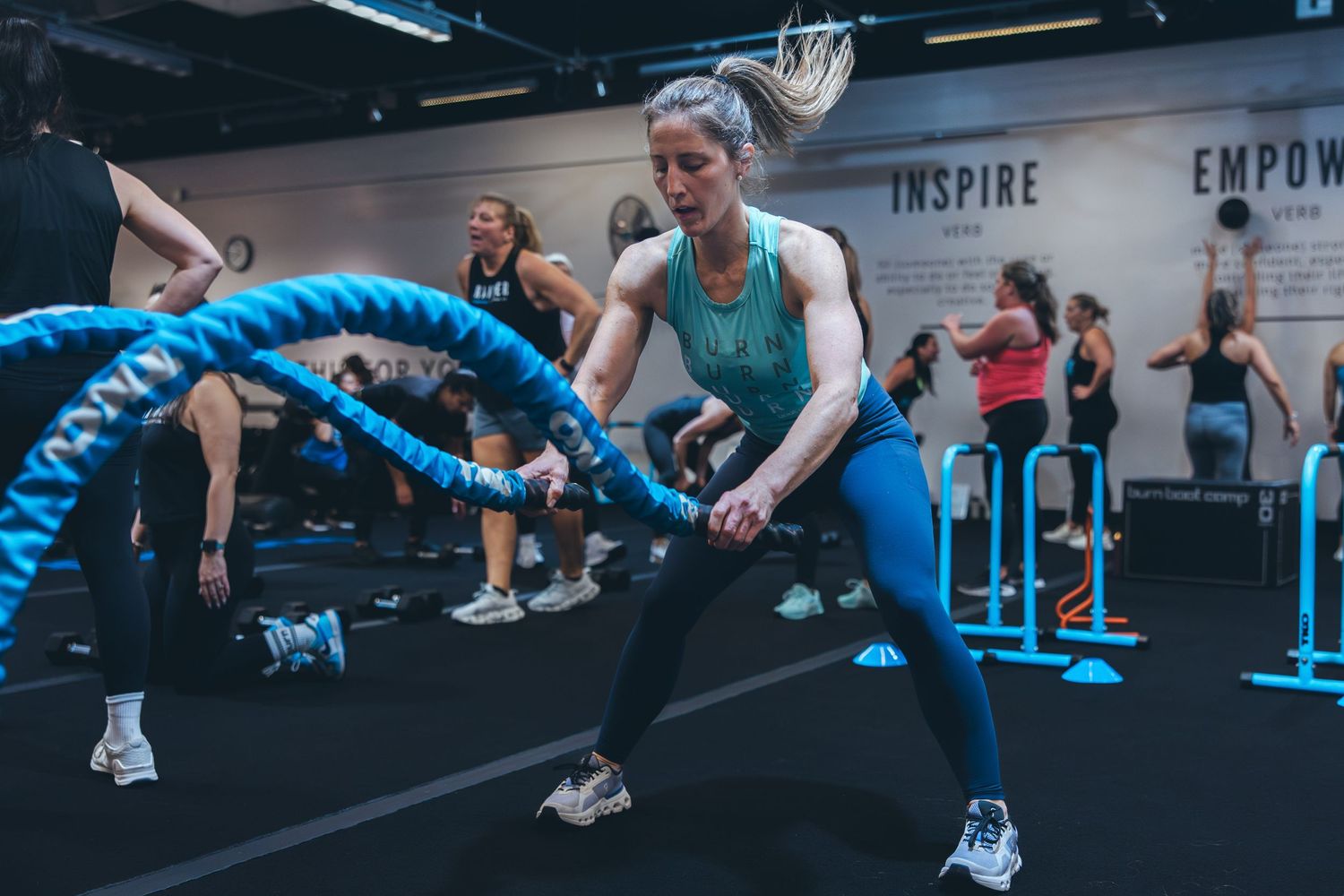 Fitness enthusiasts engage in an intense battle rope workout session in a modern gym facility.