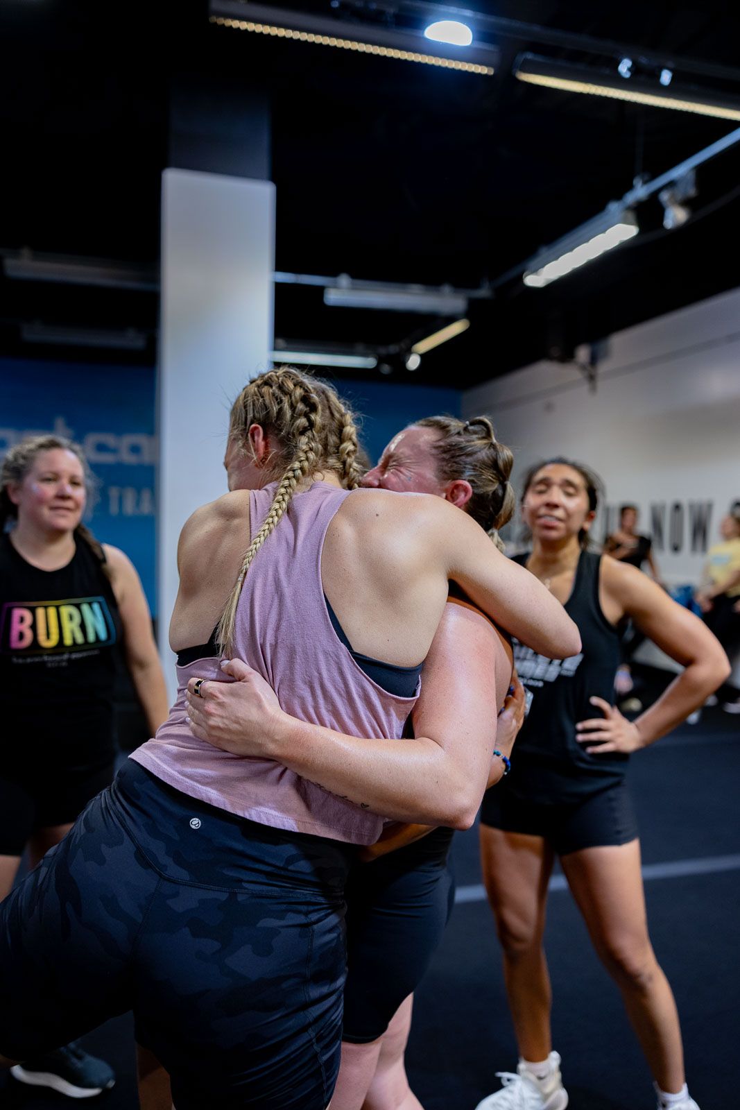 Group fitness participants stretching and cooling down after a workout class in a modern gym space.