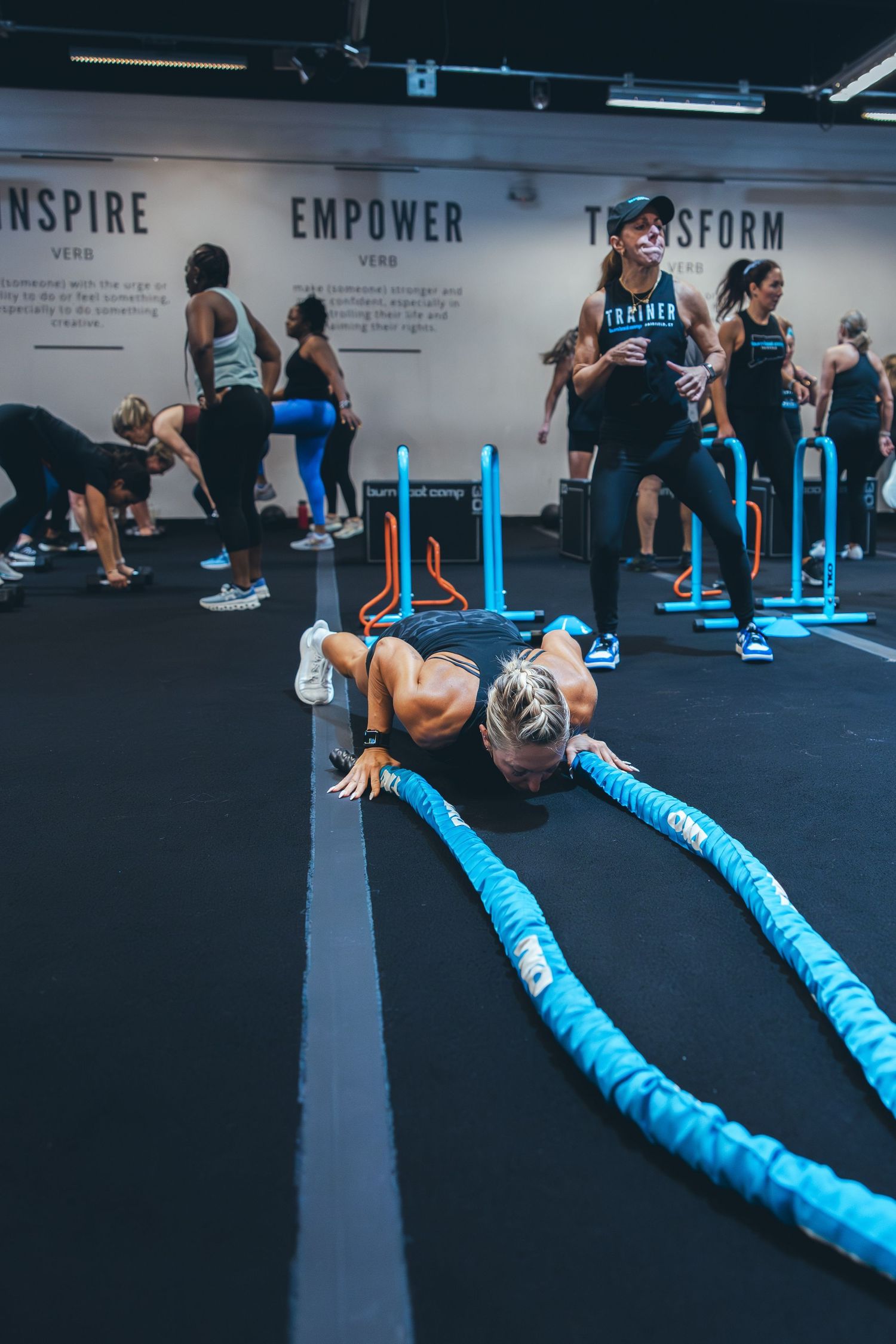 Fitness enthusiast performing battle rope exercise during high-intensity workout class.
