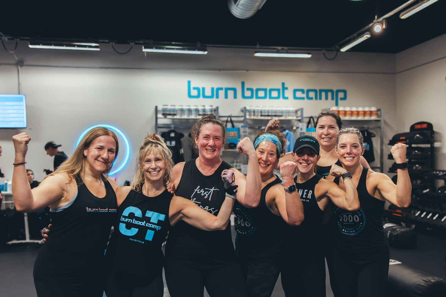 Fitness group showing off their strength with flexed arms at Burn Boot Camp.