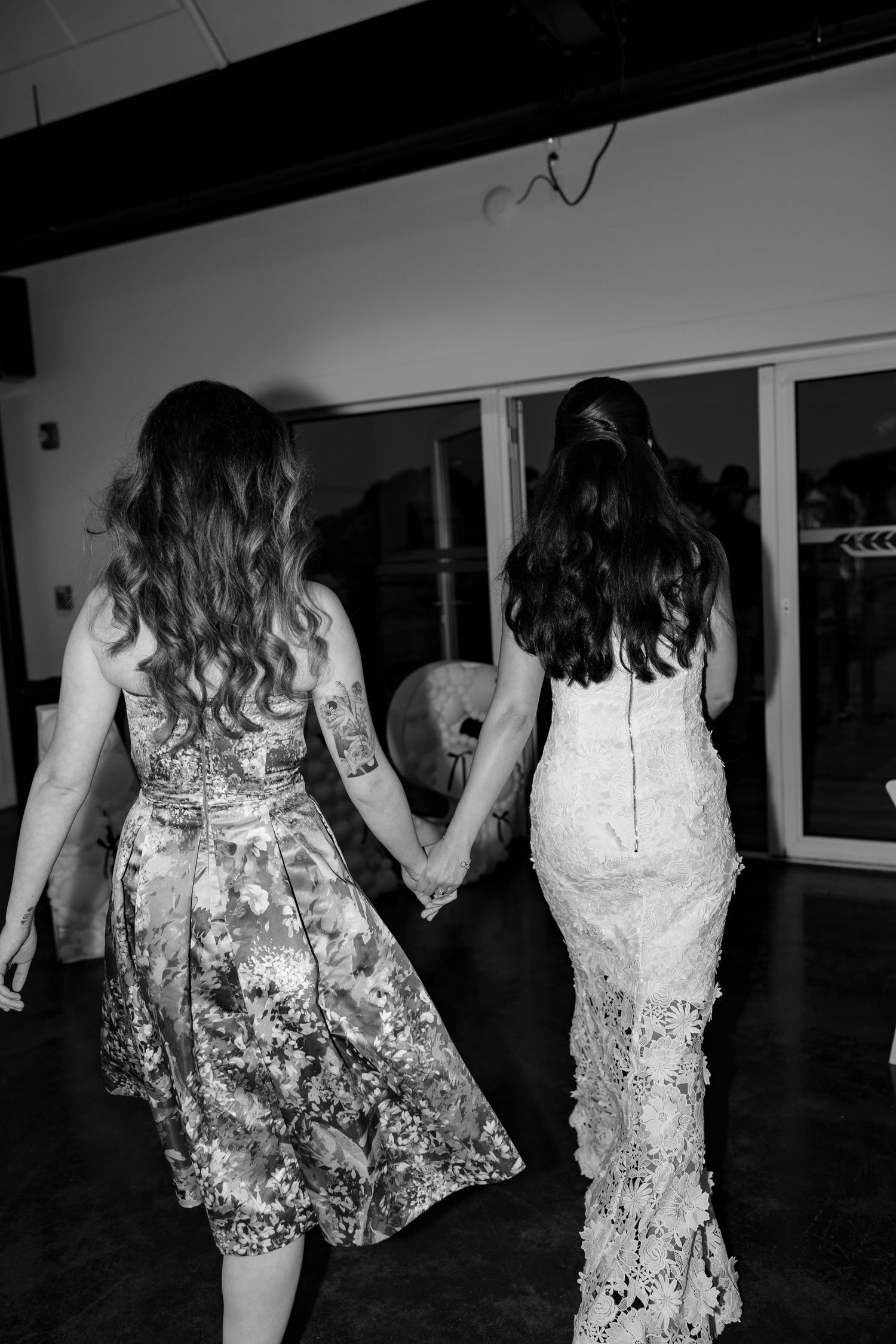 Black and white photo of people dancing in lace and floral dresses at a celebration.