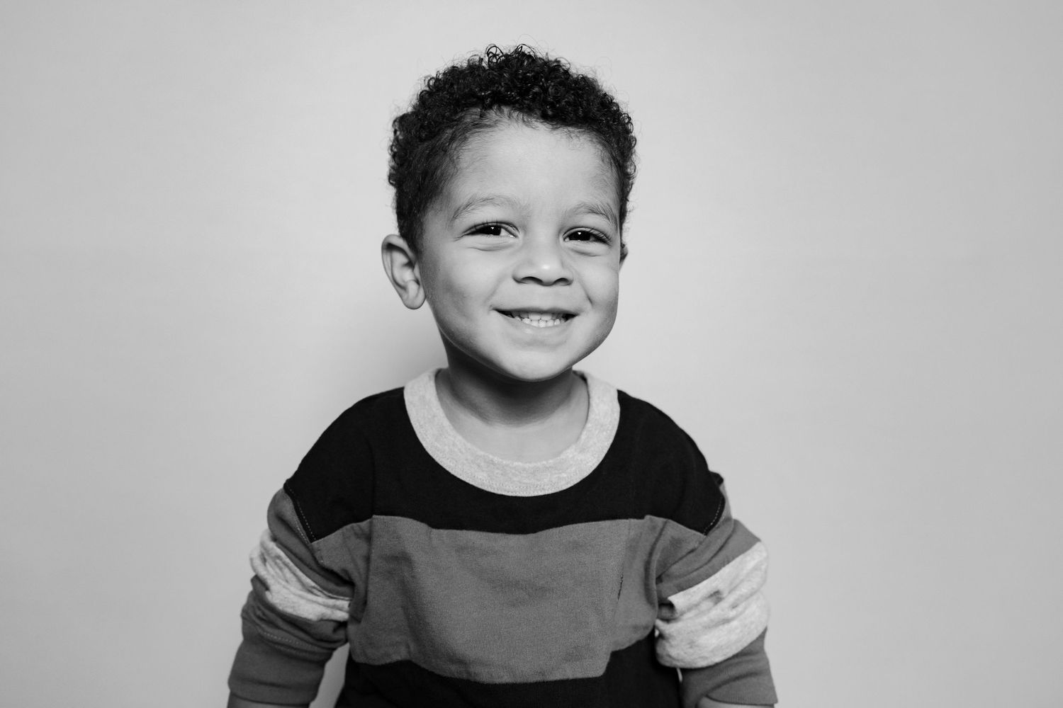 A series of black and white portrait photos showing a child's progression of expressions from neutral to smiling.