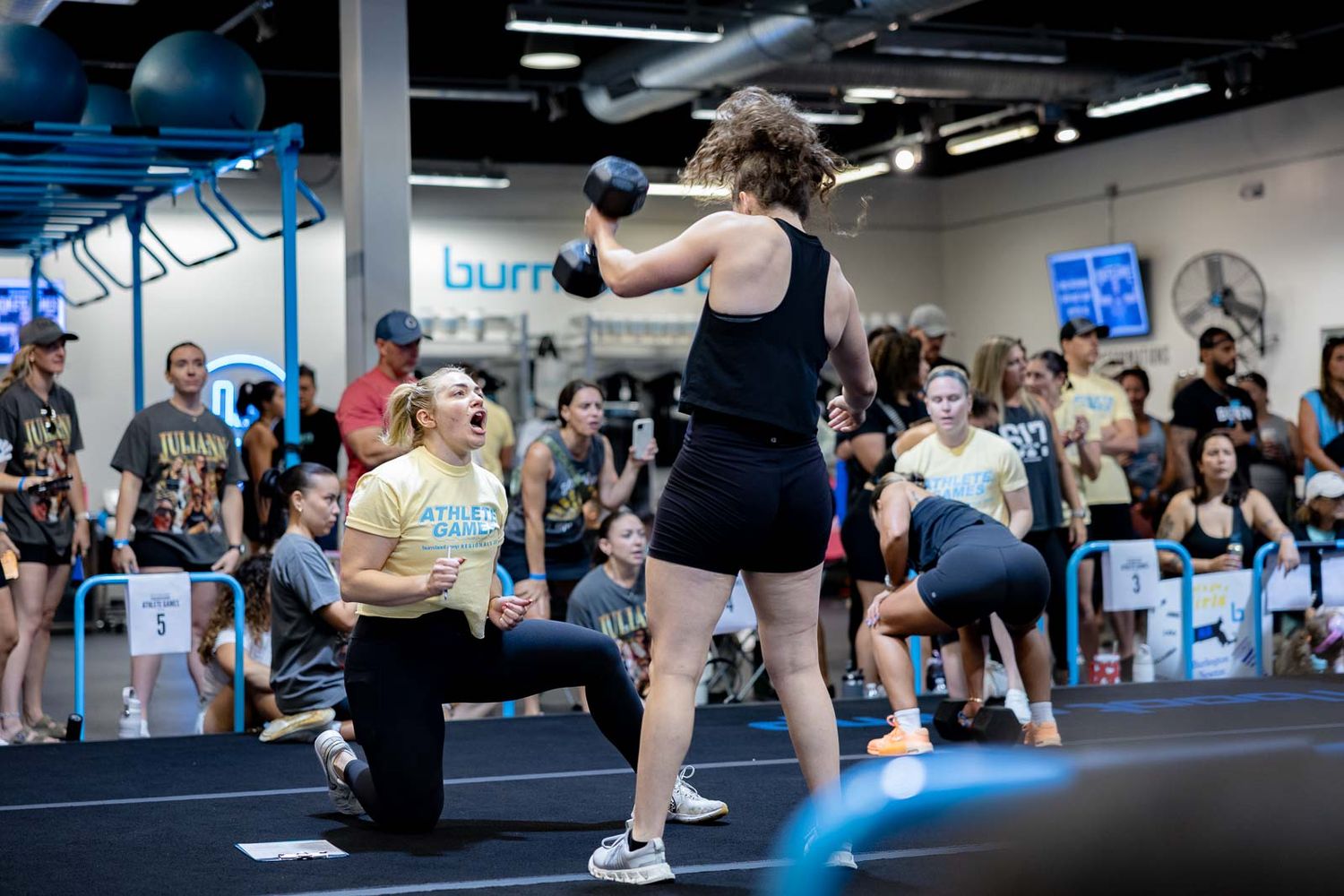 People working out together in a modern fitness studio with blue walls and exercise equipment during a training session.