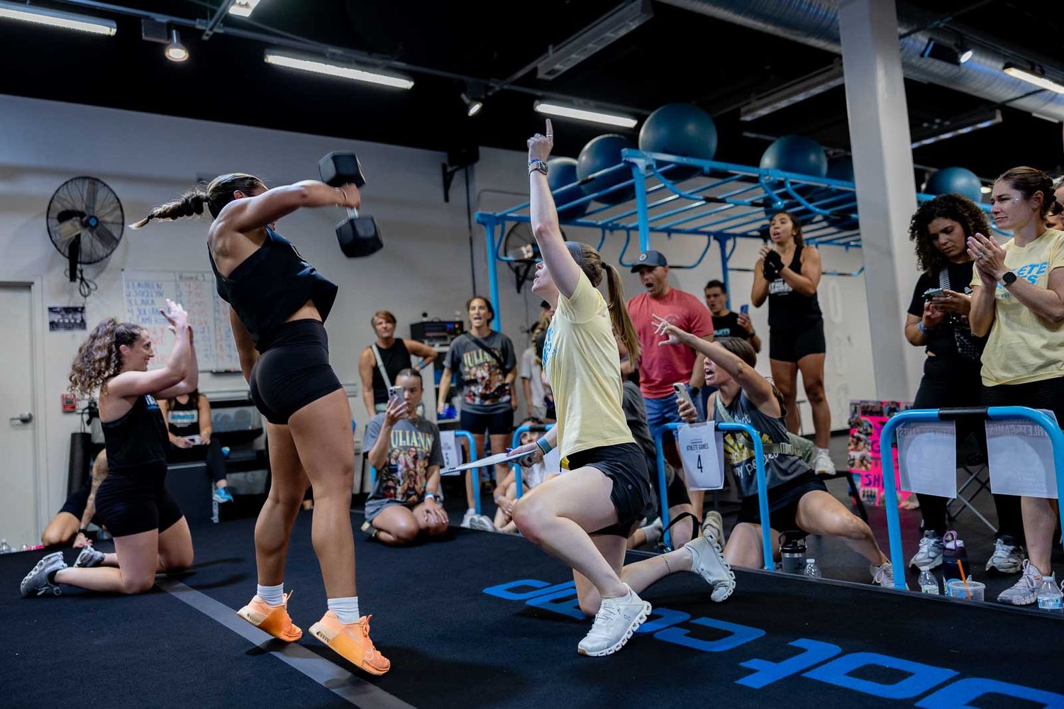Athletes performing burpee exercises in synchronized formation during an intense group fitness workout.