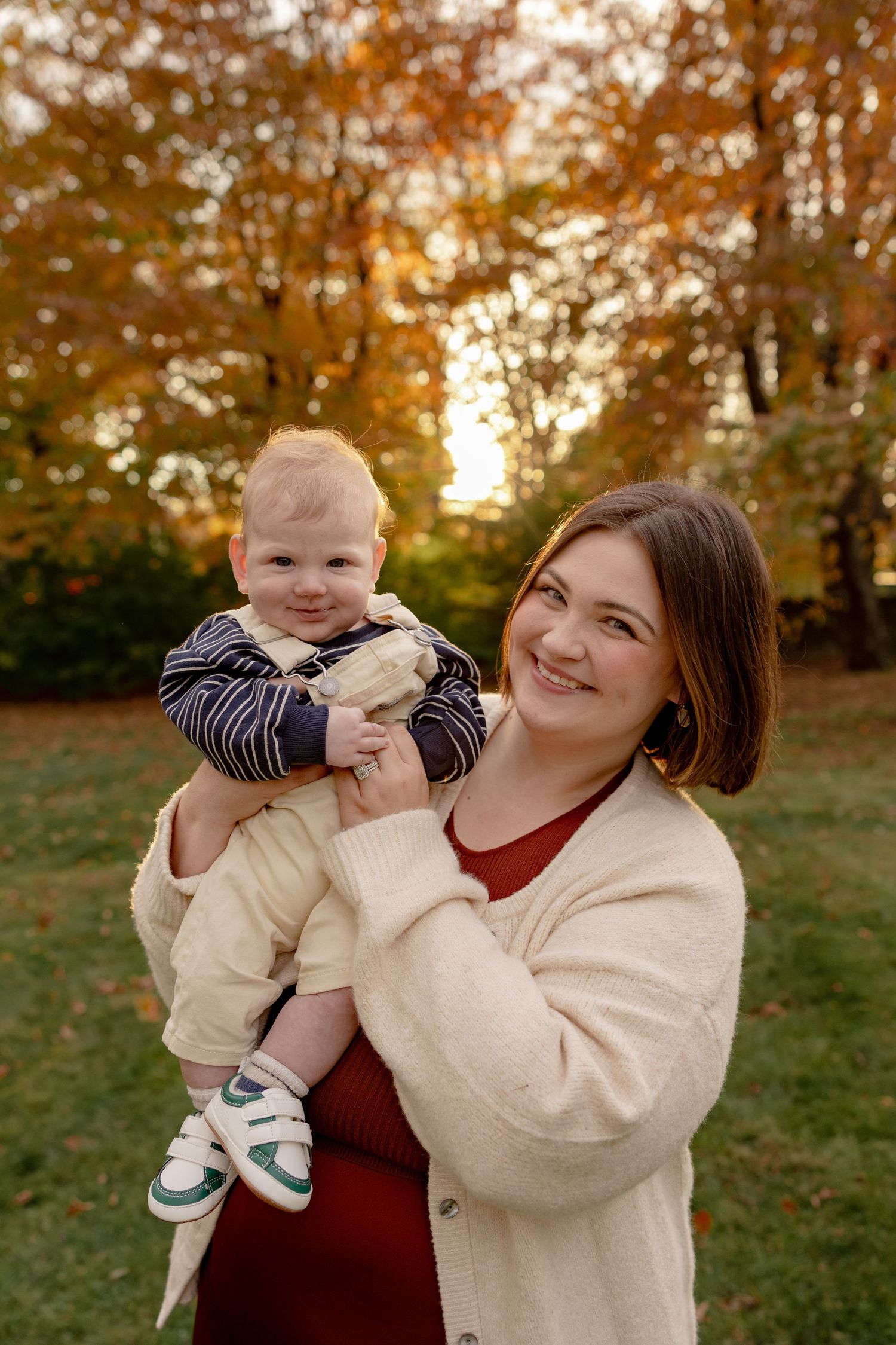 A warm autumn scene outdoors with golden trees and sunlight creating a cozy atmosphere during a family photoshoot.