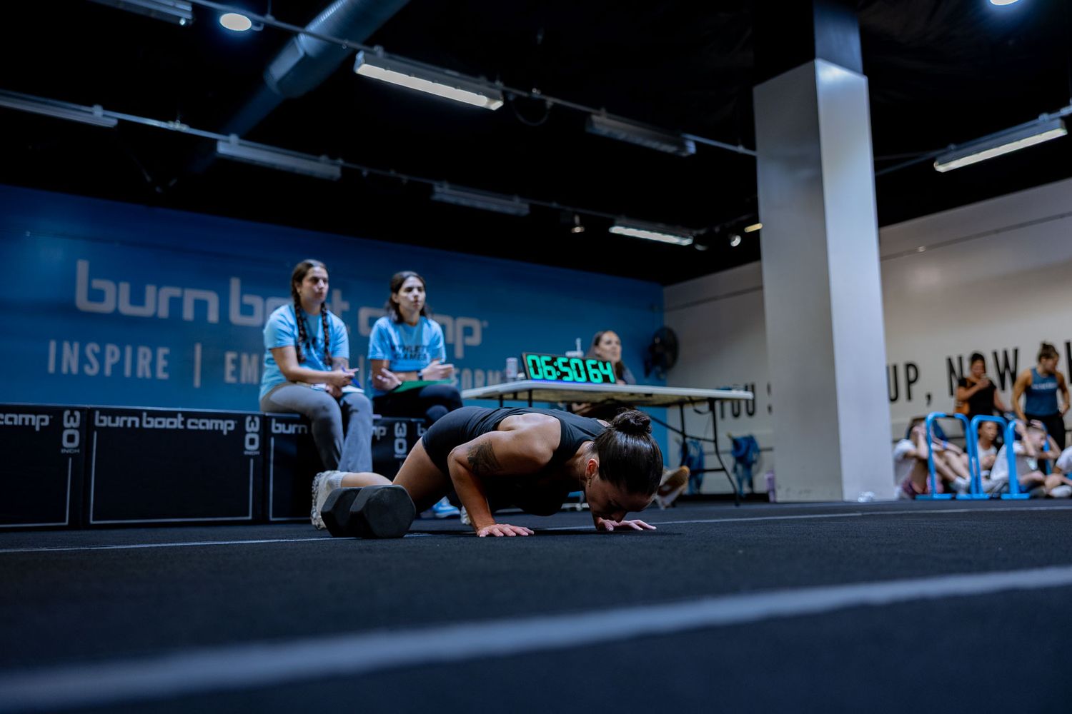 Athletes perform a synchronized plank exercise during an indoor fitness class at a gym.
