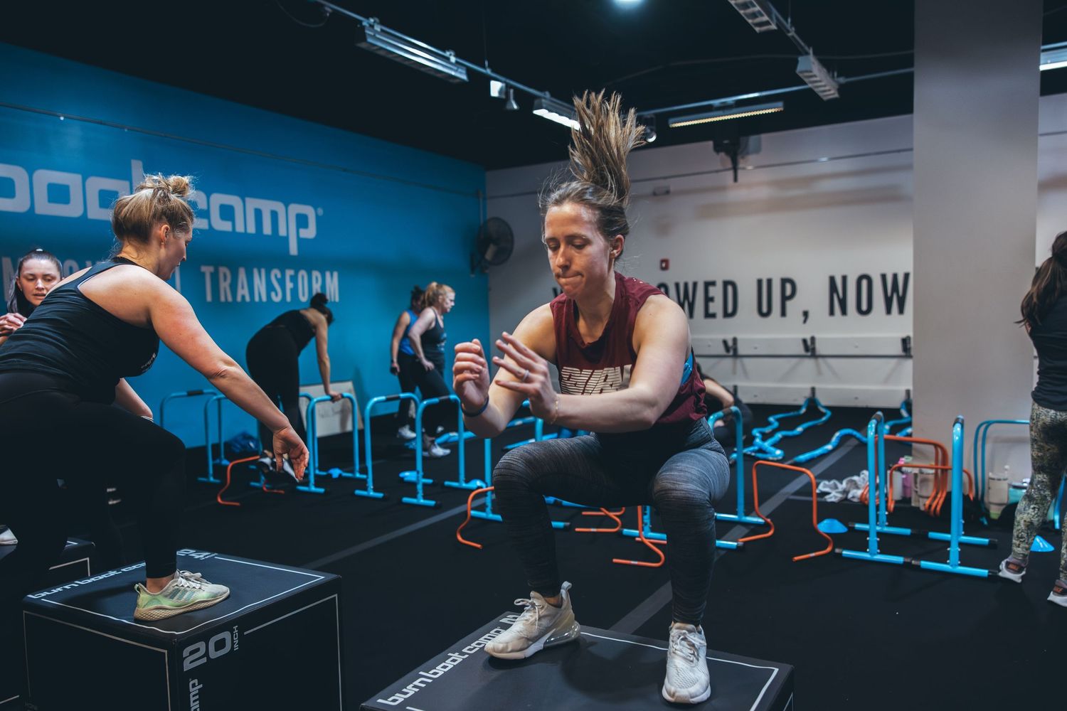 Two athletes doing synchronized box jump exercises during intense workout session.