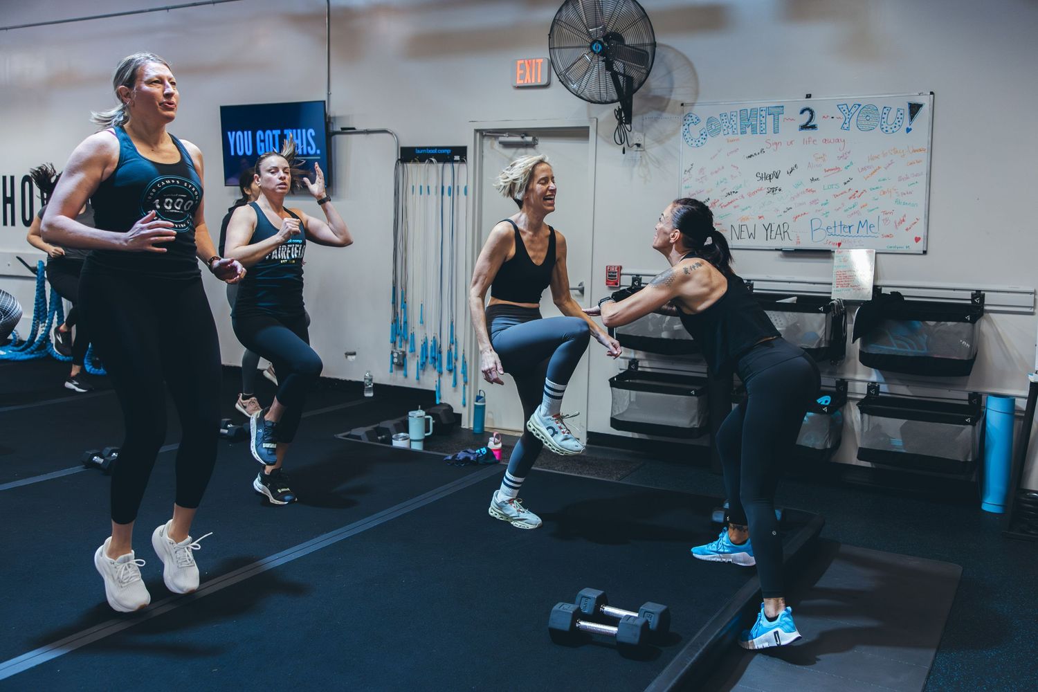 Group of fitness participants doing jumping exercises during boot camp class.