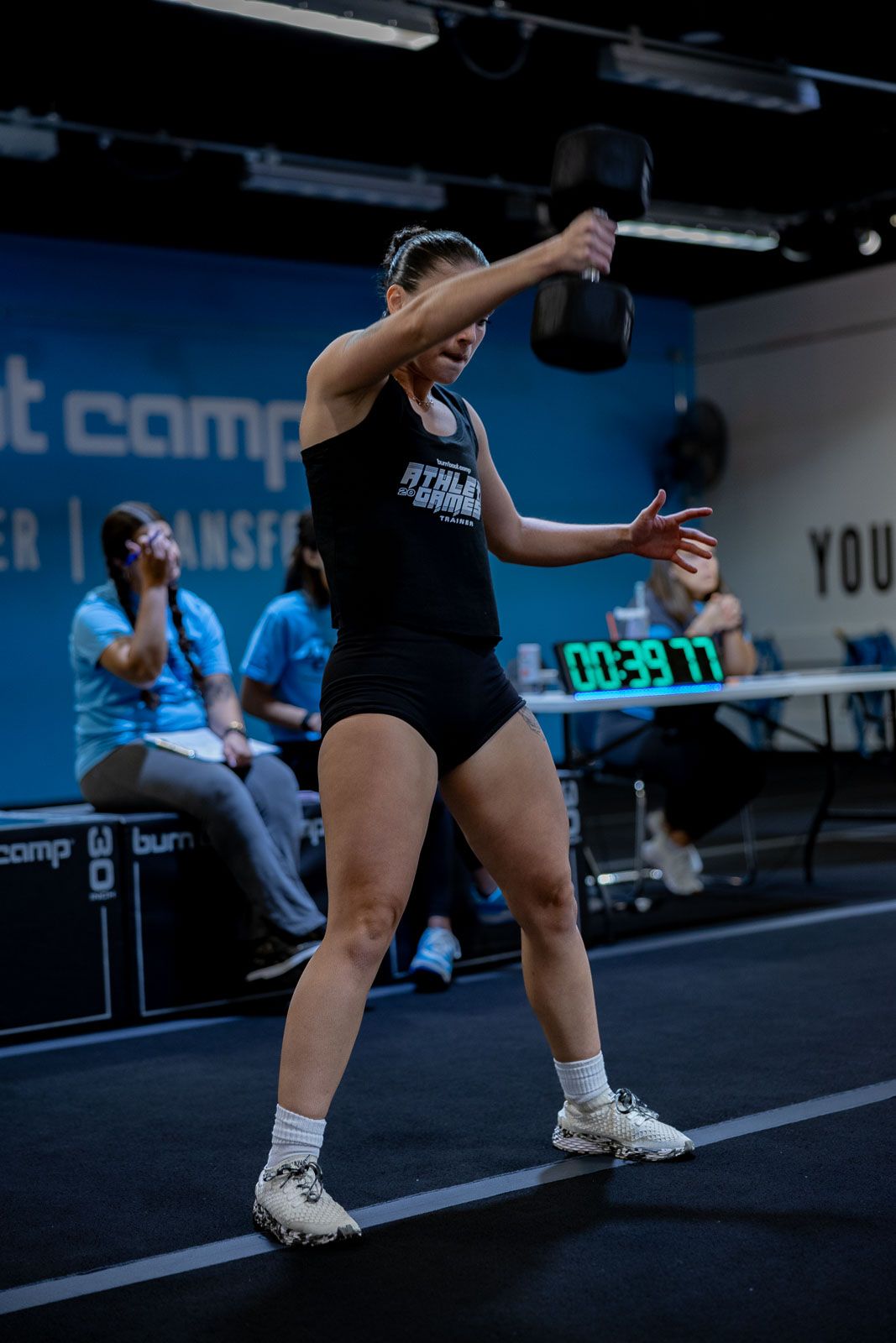 Athletes performing dynamic stretching exercises on a dark floor in a fitness facility.
