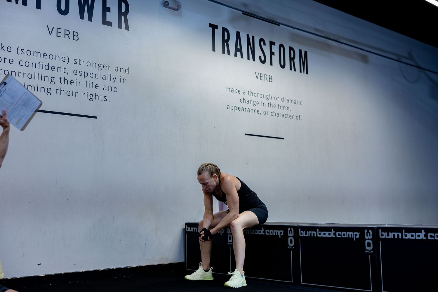 An athlete takes a rest break on a weight bench against a wall with motivational text about transformation.