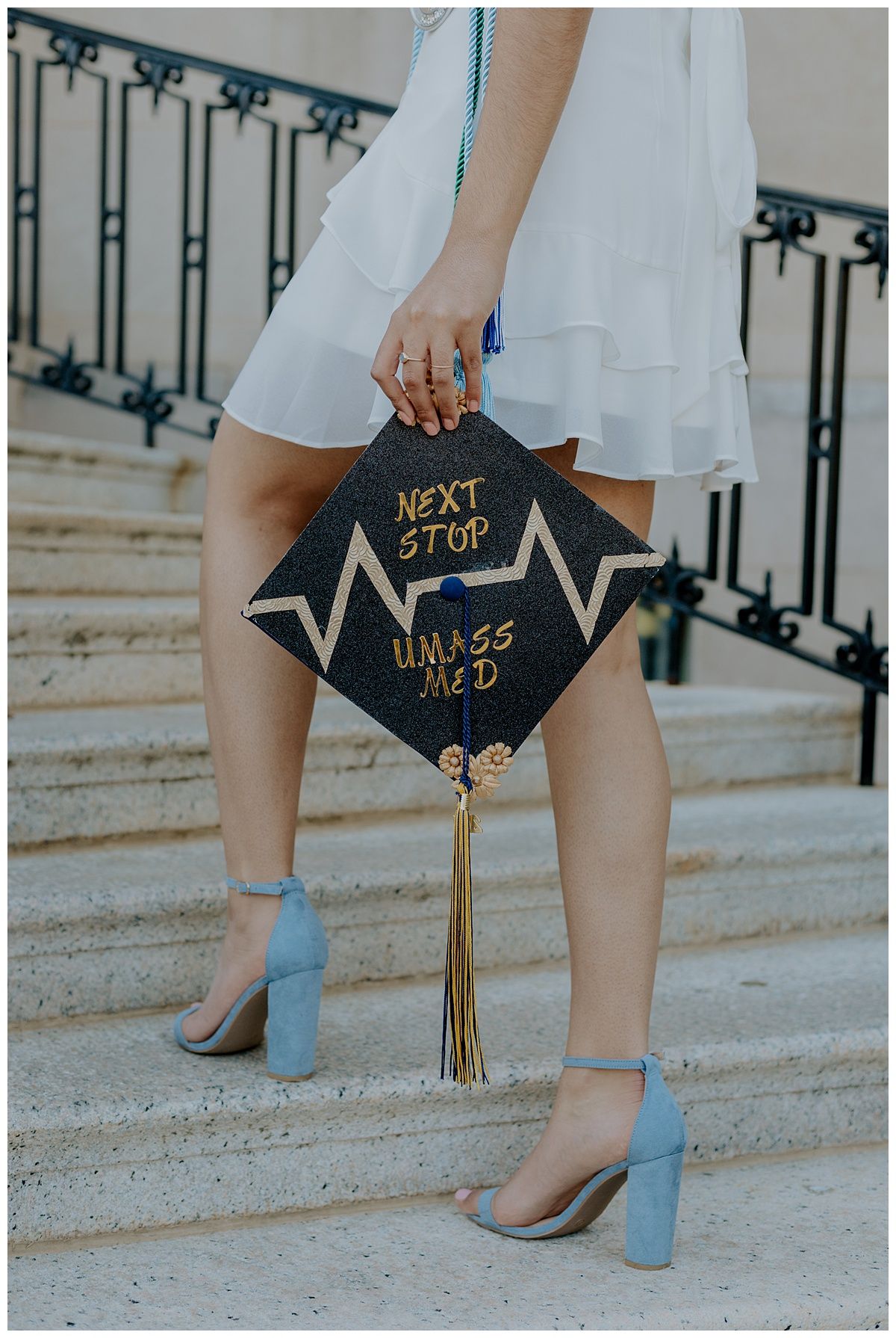 Close-up of decorated graduation cap with Next Stop message and blue heels on stairs.