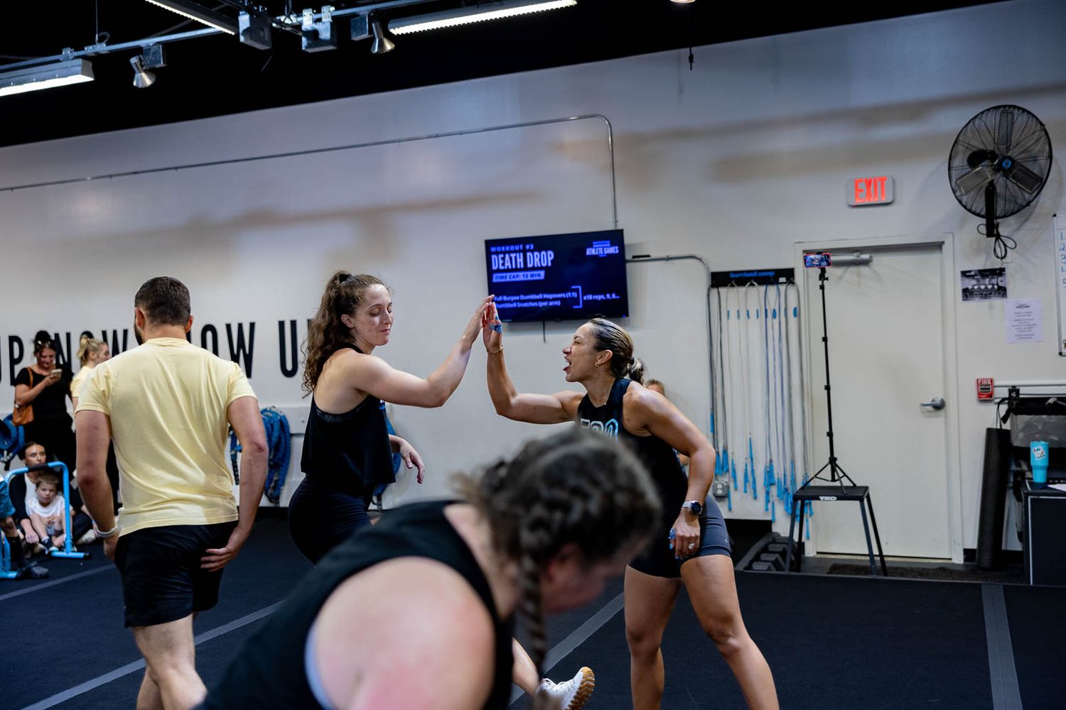 Athletes high-fiving and encouraging each other during an intense workout session in a fitness facility.