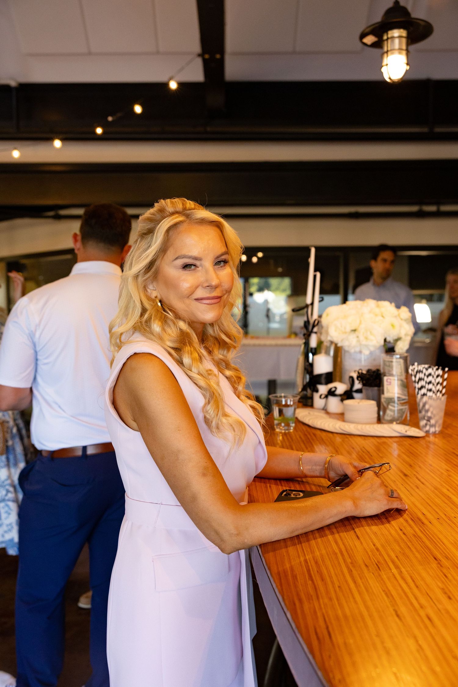 Wedding reception venue with wooden bar top and hanging pendant lights creating cozy ambiance.