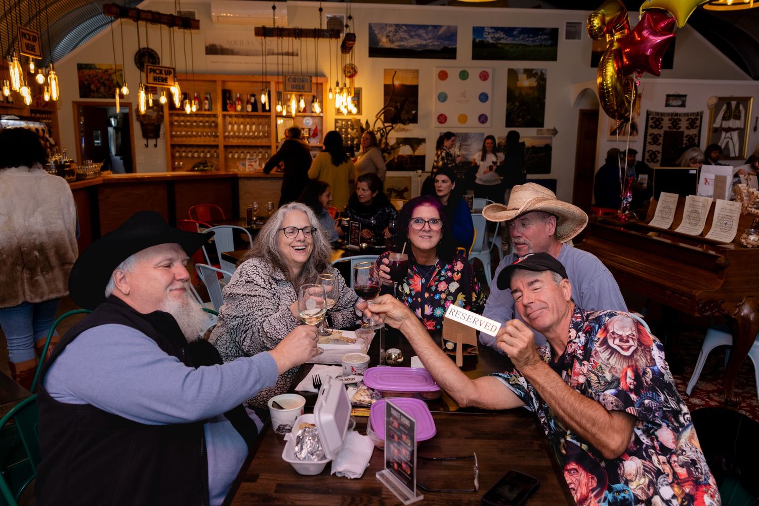 A group of people enjoying drinks and socializing at a dimly lit bar or restaurant establishment.