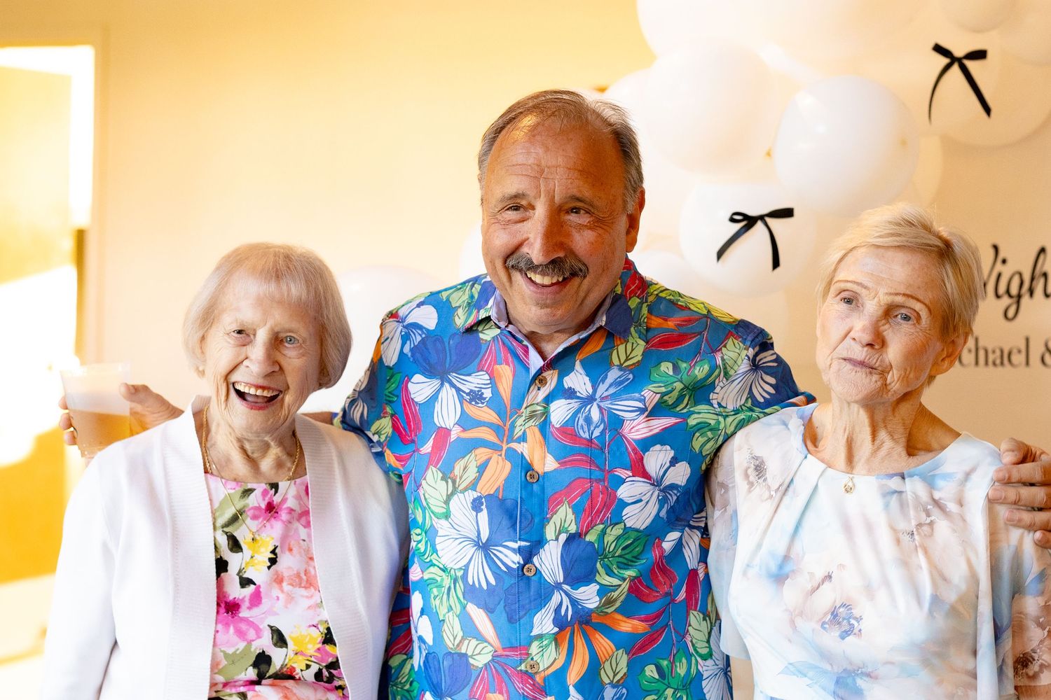 Guests in colorful floral attire share joyful moments at a celebration.