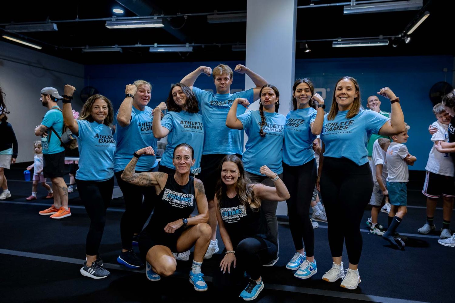 Group of people wearing matching light blue shirts pose together in an indoor exercise or fitness facility.