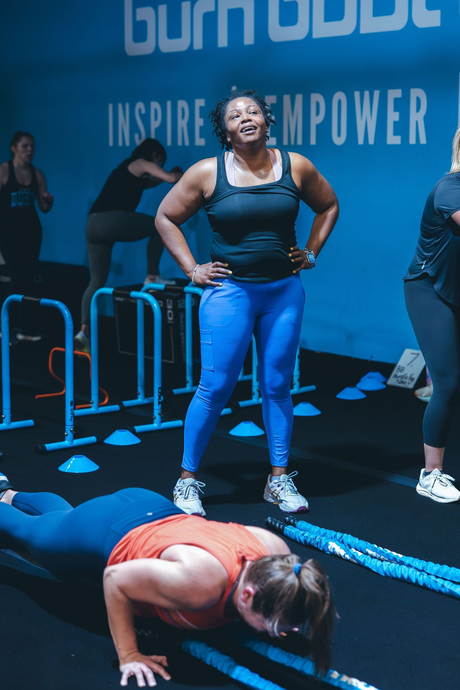 Fitness class participants engaged in floor exercises with motivational wall text in background.