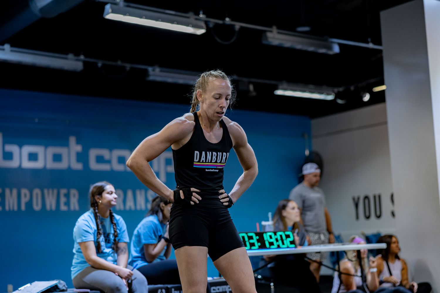 Athletic training scene indoors with dark exercise attire against blue wall in fitness studio setting.