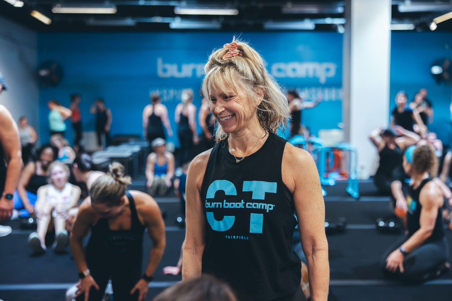 Fitness instructor in blue and white logo tank top leading class at Burn Boot Camp.