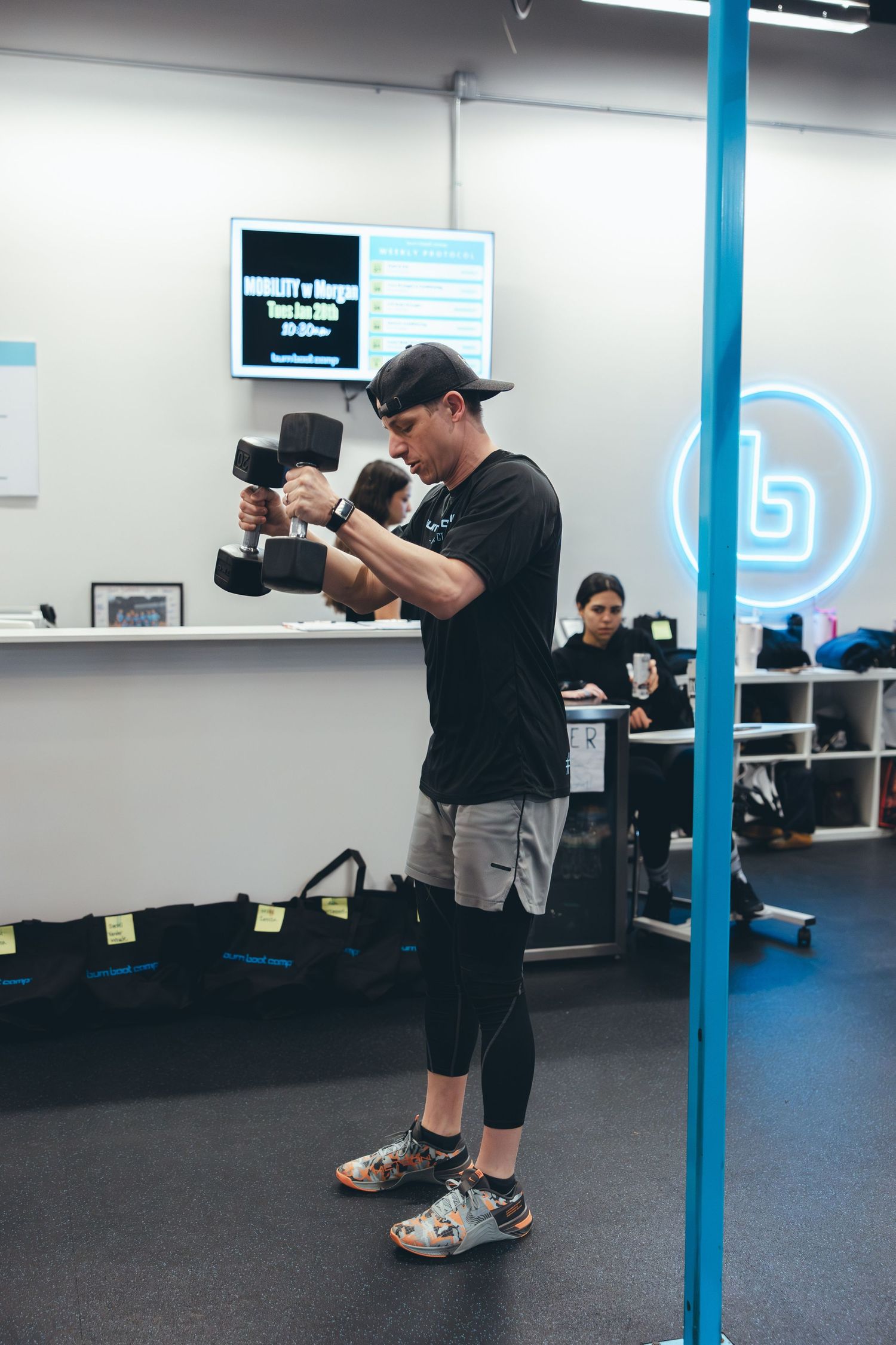 Person performing dumbbell exercises while checking form in a modern fitness facility.