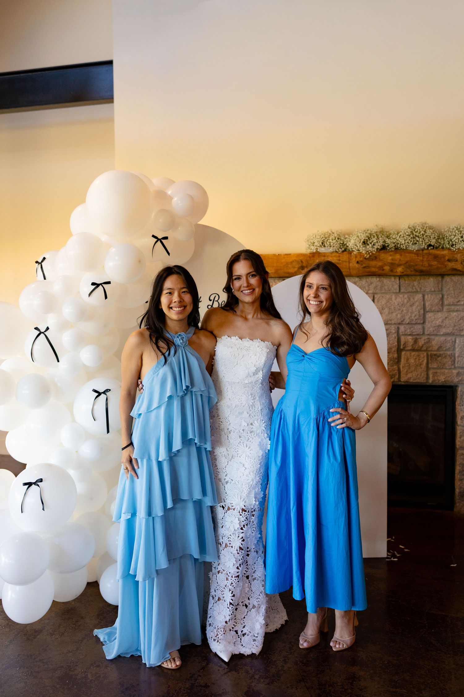 Group photo showing attendees in coordinating light blue dresses and white gowns at a wedding celebration.