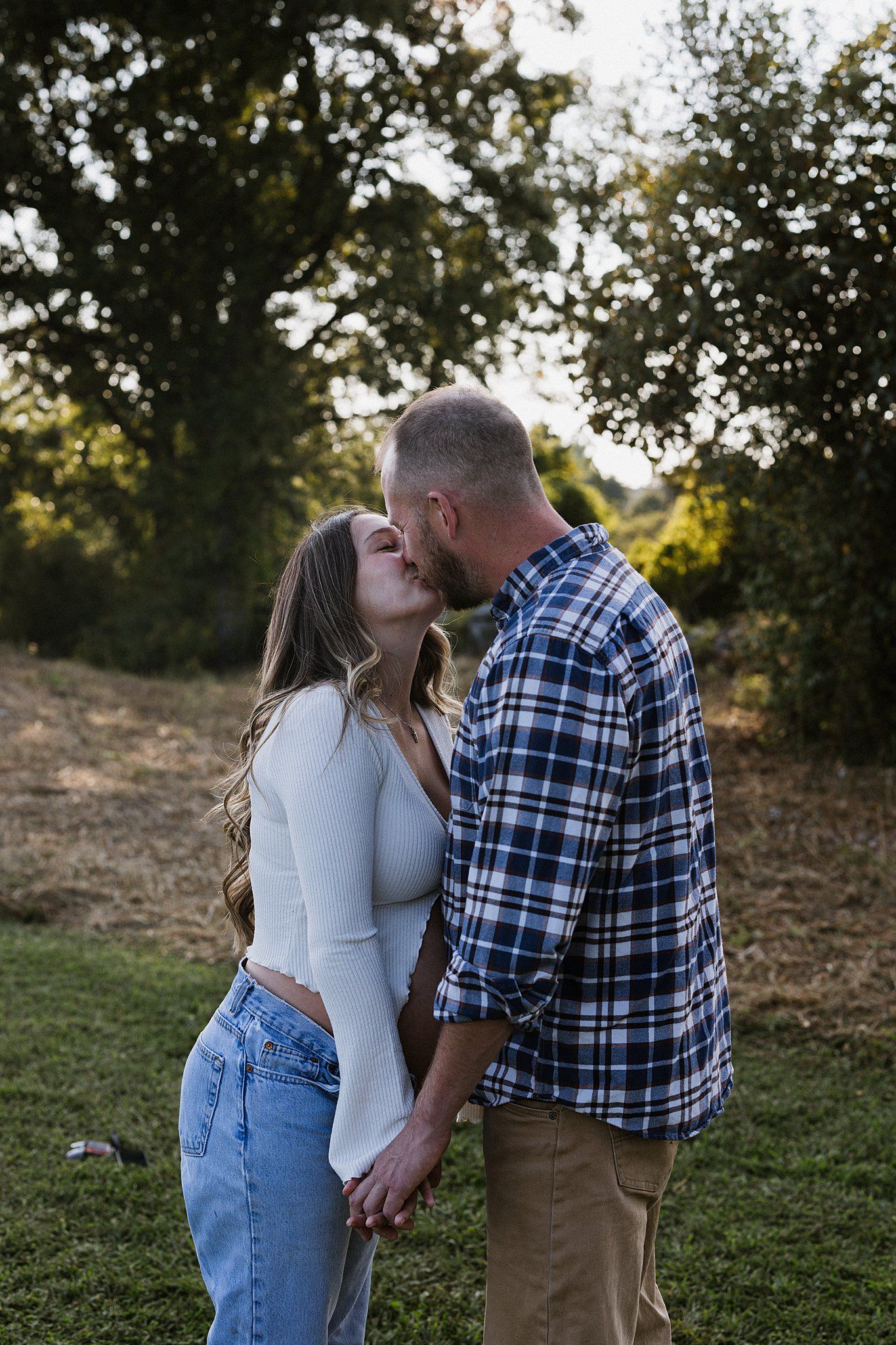 Romantic couple sharing a tender kiss in a natural outdoor setting.