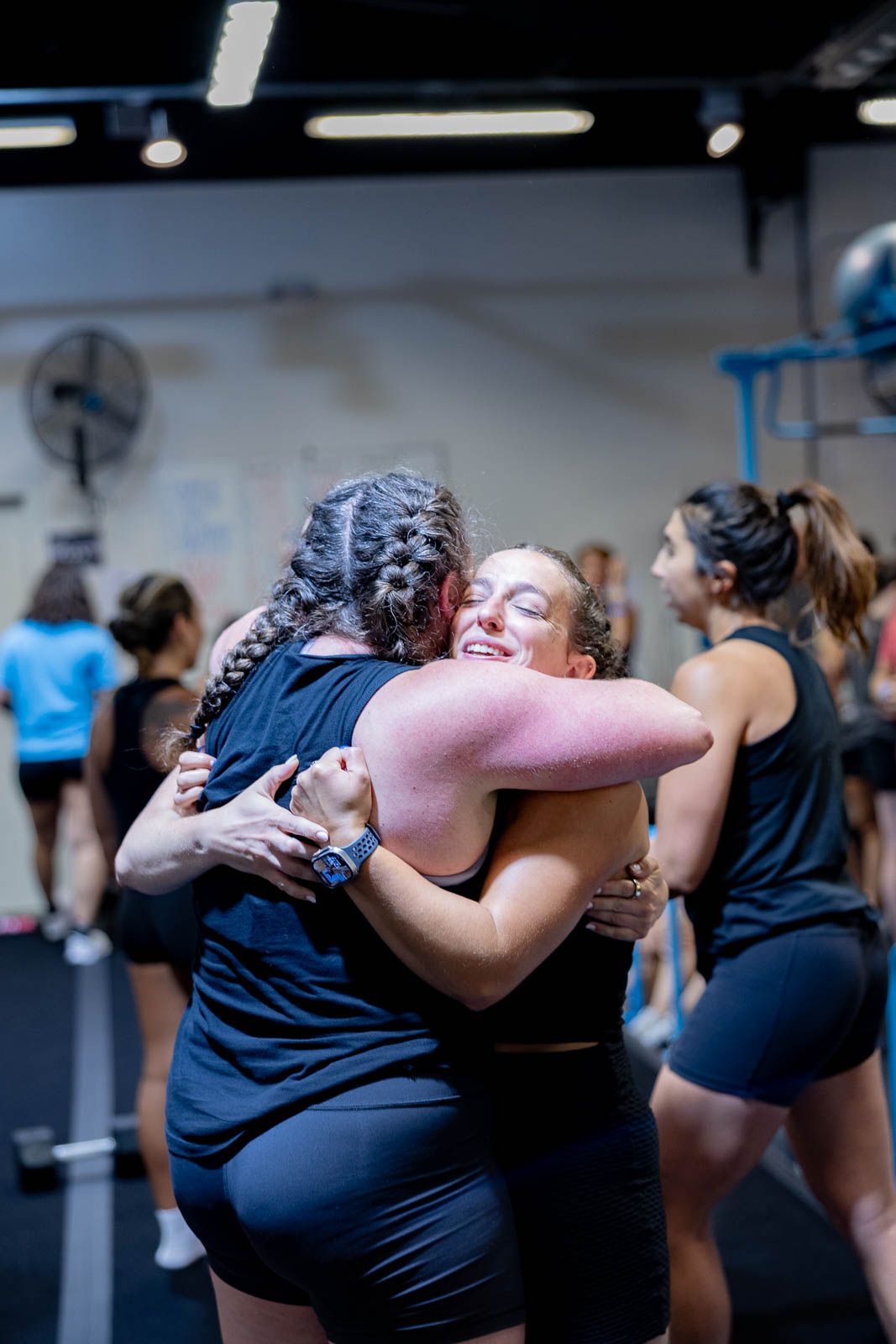 People sharing emotional embraces and celebrating achievements in a fitness community setting.