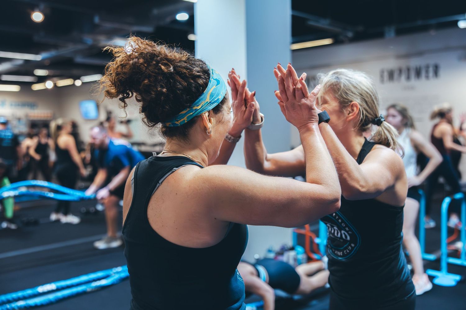 Two people high-fiving during an energetic workout class in a modern fitness studio.