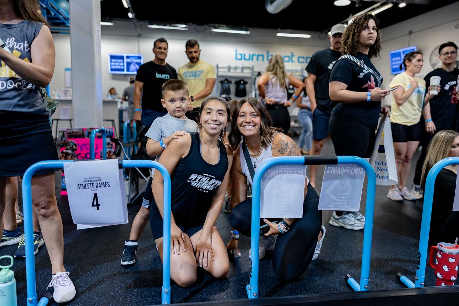People participating in a group fitness class with dumbbells and exercise equipment at a gym facility.