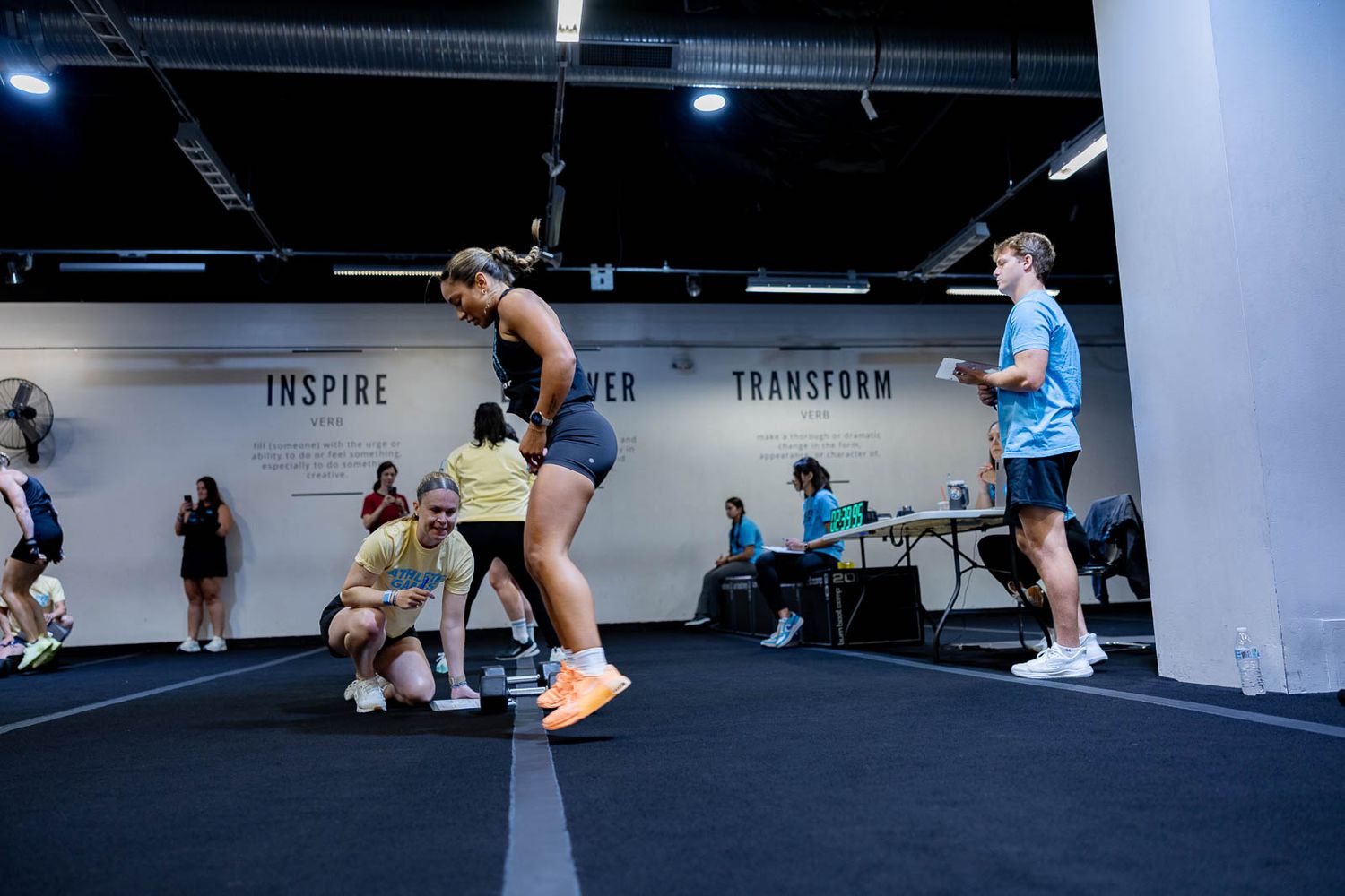 Athletes perform dynamic exercises during an intense workout session at a fitness facility.