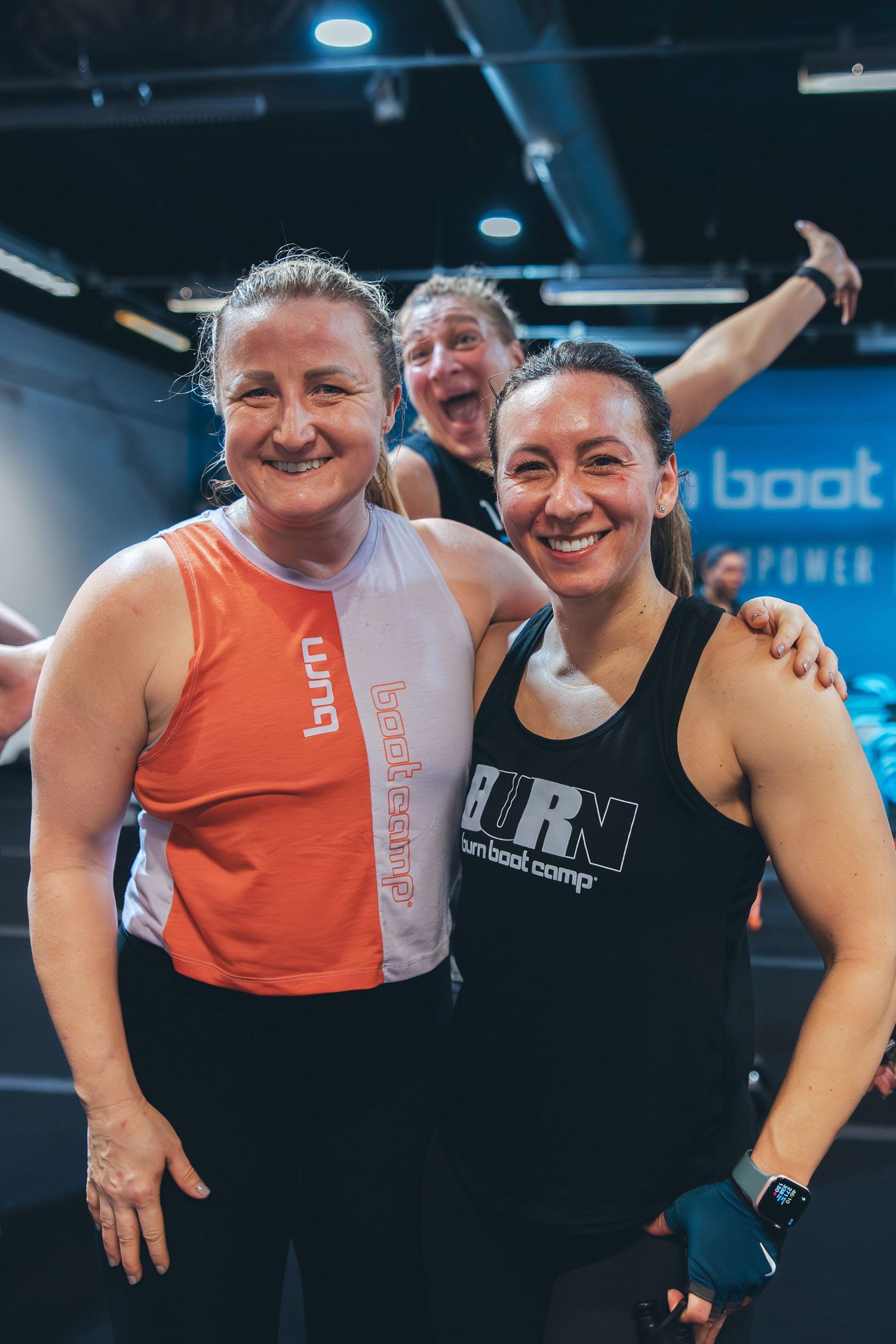Two athletes in workout attire posing together at a modern gym facility.