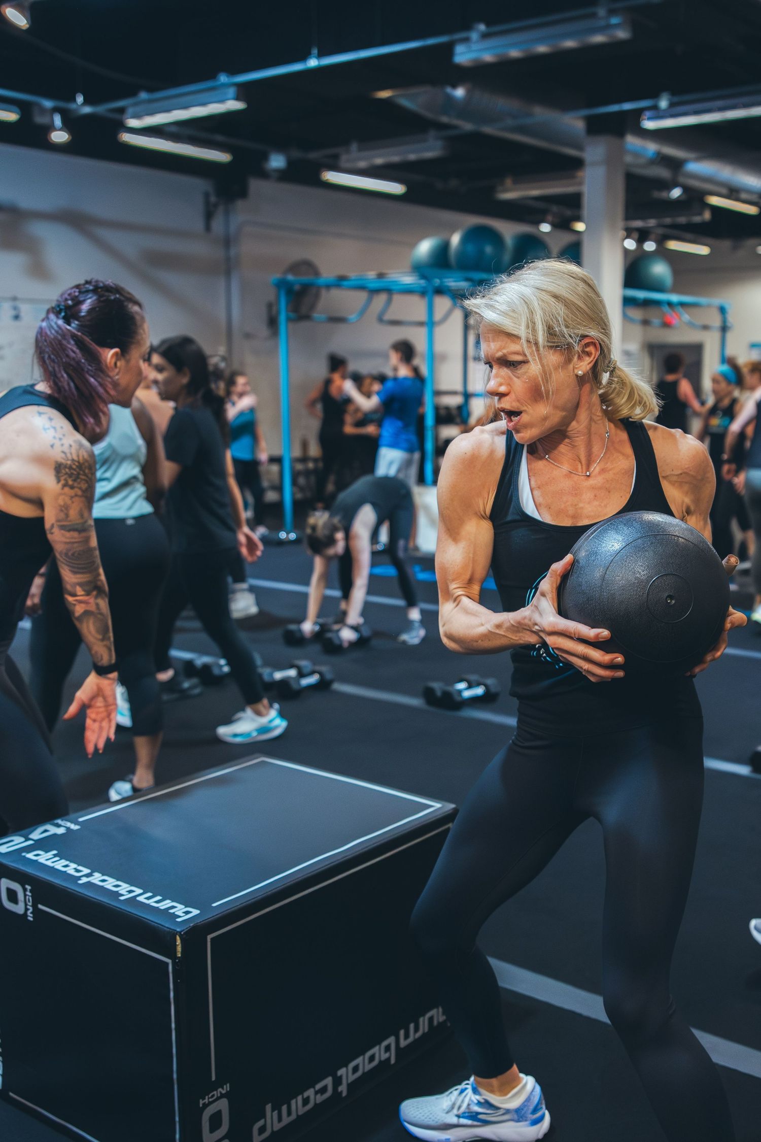 Athlete performing exercises with a medicine ball at a fitness class in a modern gym facility.