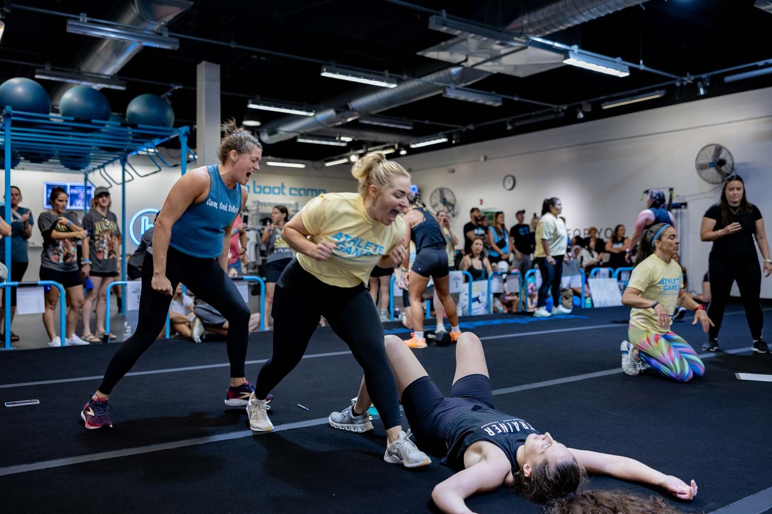 Athletes perform dynamic exercises and stretches in a modern fitness studio with industrial-style lighting.
