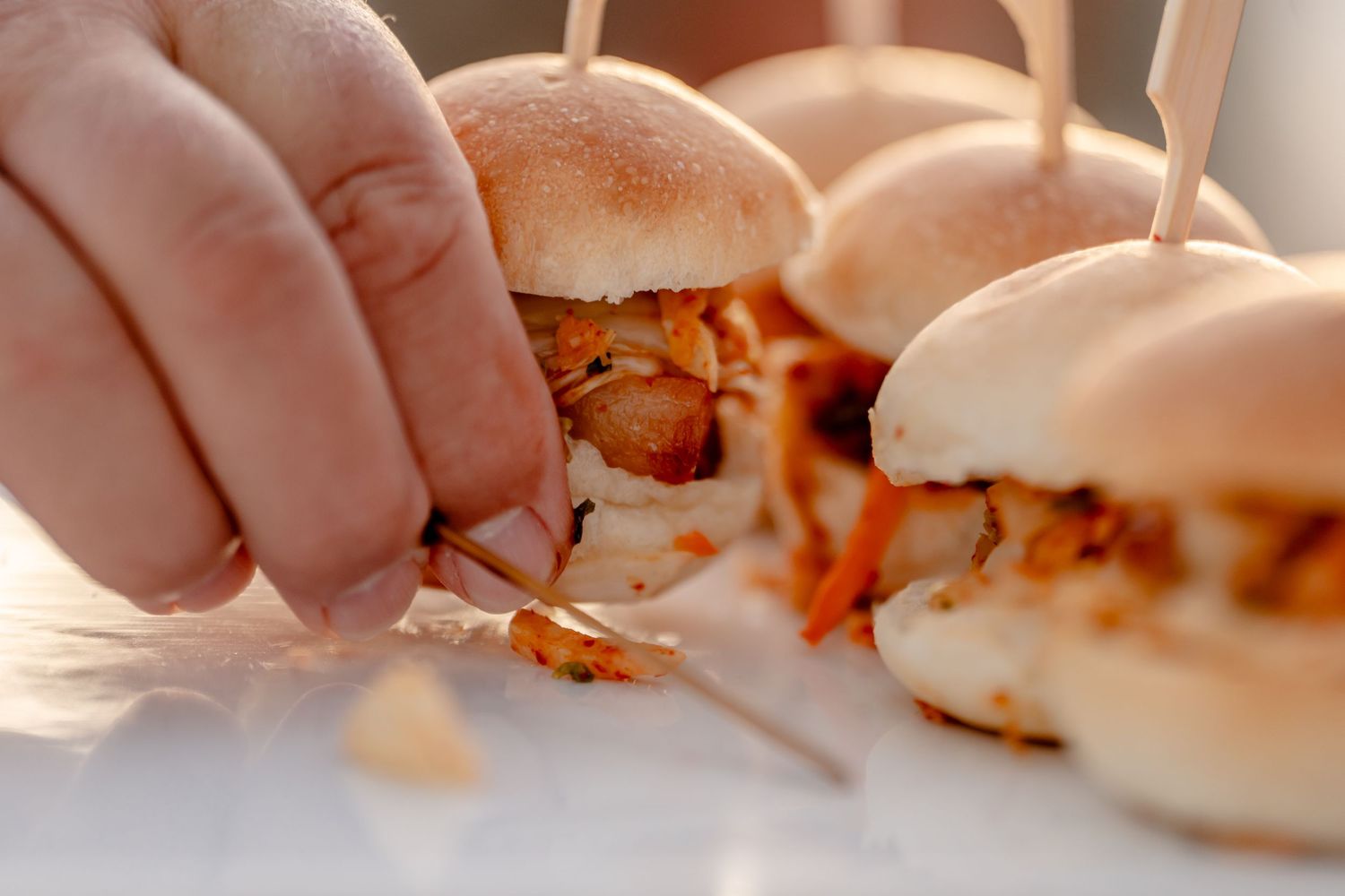 Close-up of small appetizer sandwiches being arranged on a serving plate.