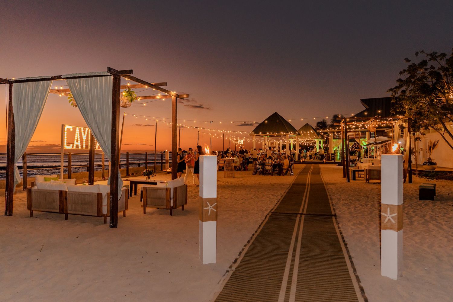 Beach walkway and structures silhouetted against a dramatic sunset sky.