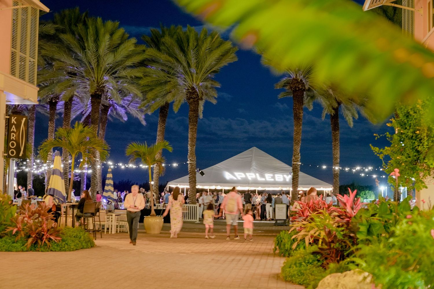 Palm tree-lined venue at night with event tents and string lights creating an ambient atmosphere.