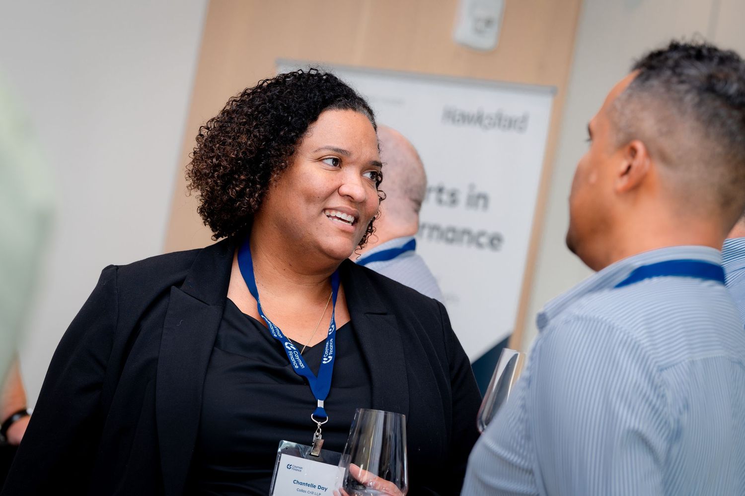 Business professionals engage in animated networking conversation at a corporate event.