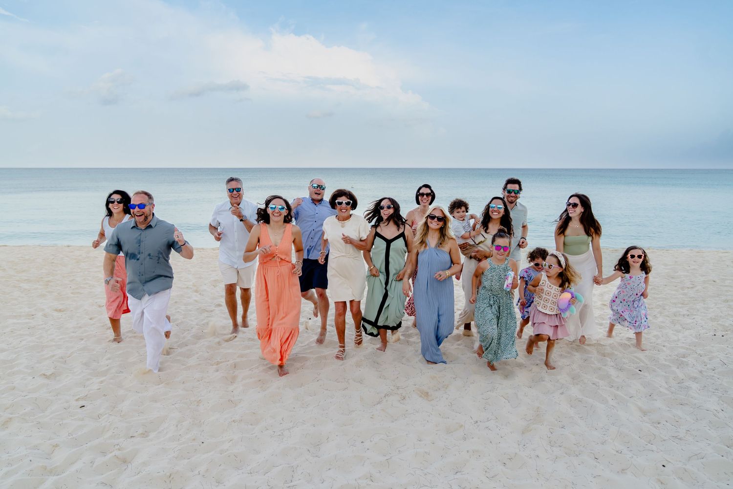 Joyful gathering of people walking along a beautiful beach with calm waters and cloudy sky.