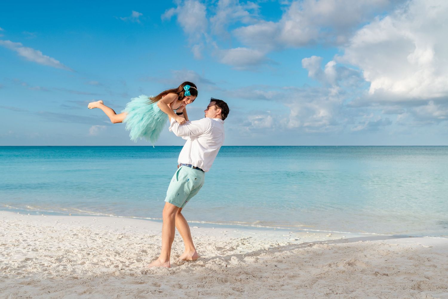 People enjoying a tropical beach vacation with crystal clear turquoise waters and white sand under blue skies.