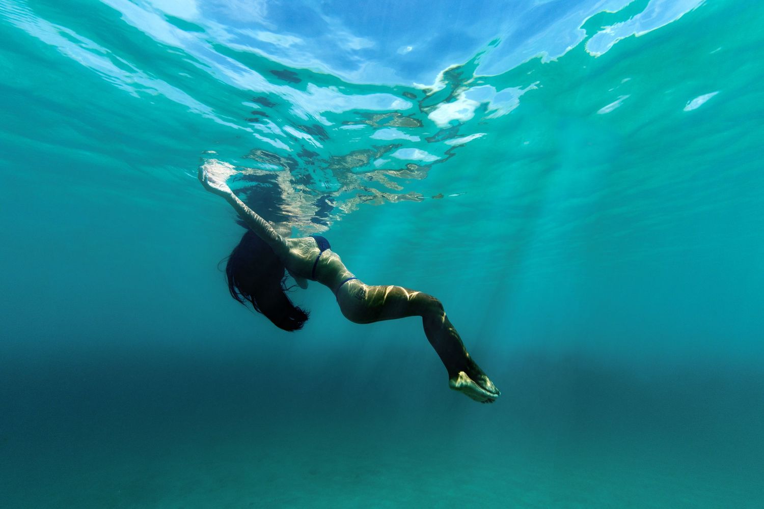 Snorkeler exploring beneath the surface of turquoise tropical waters.