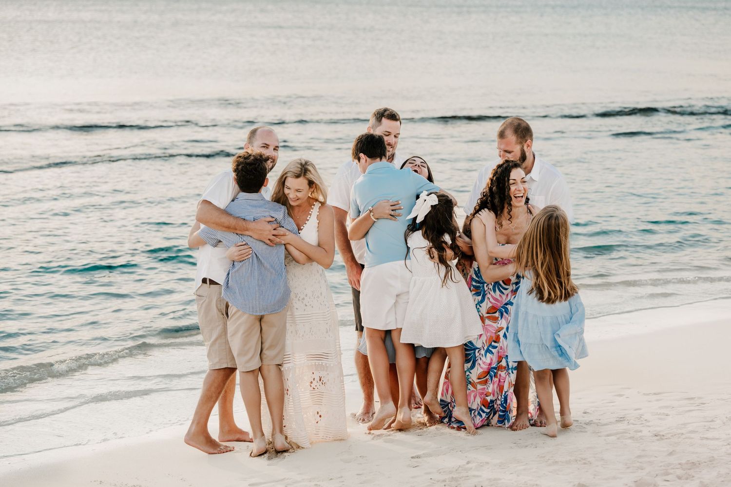 Large family group enjoying candid moments during a professional beach photography session.
