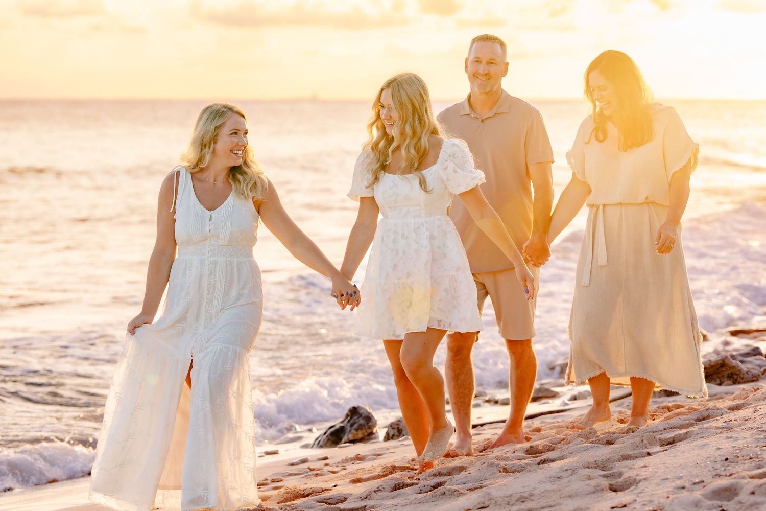 Family group walking along beach shoreline during golden hour photo session.
