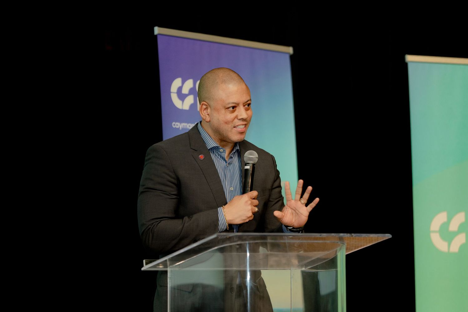 Speaker delivers presentation at podium with Cayman Finance branded backdrop.