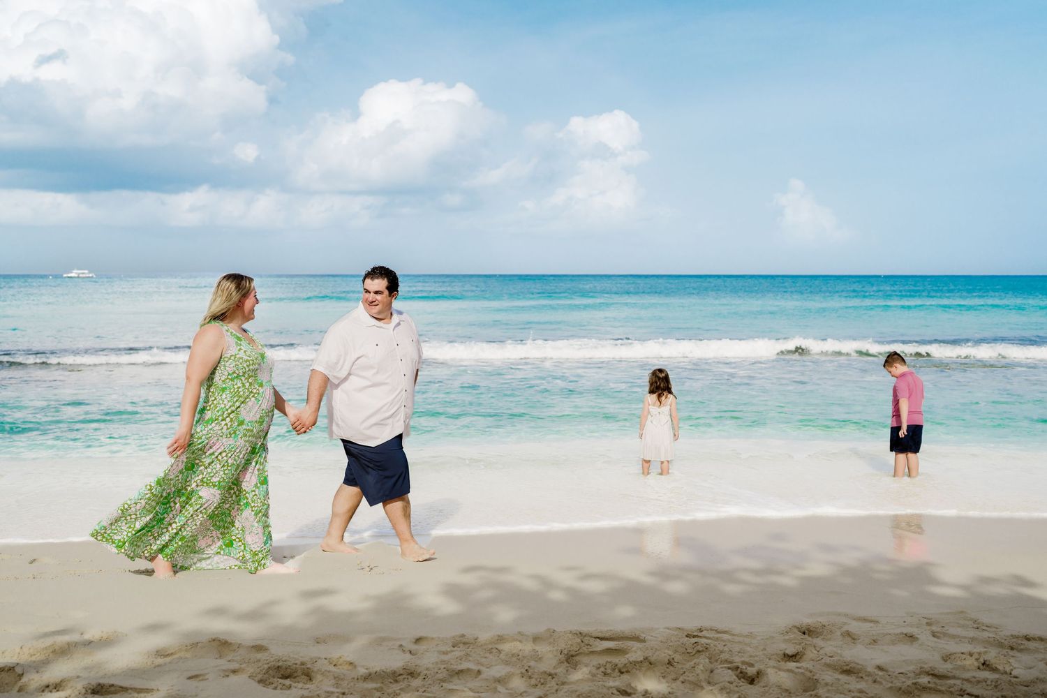 Scenic beach photoshoot with people walking along the shoreline as waves crash on white sand.