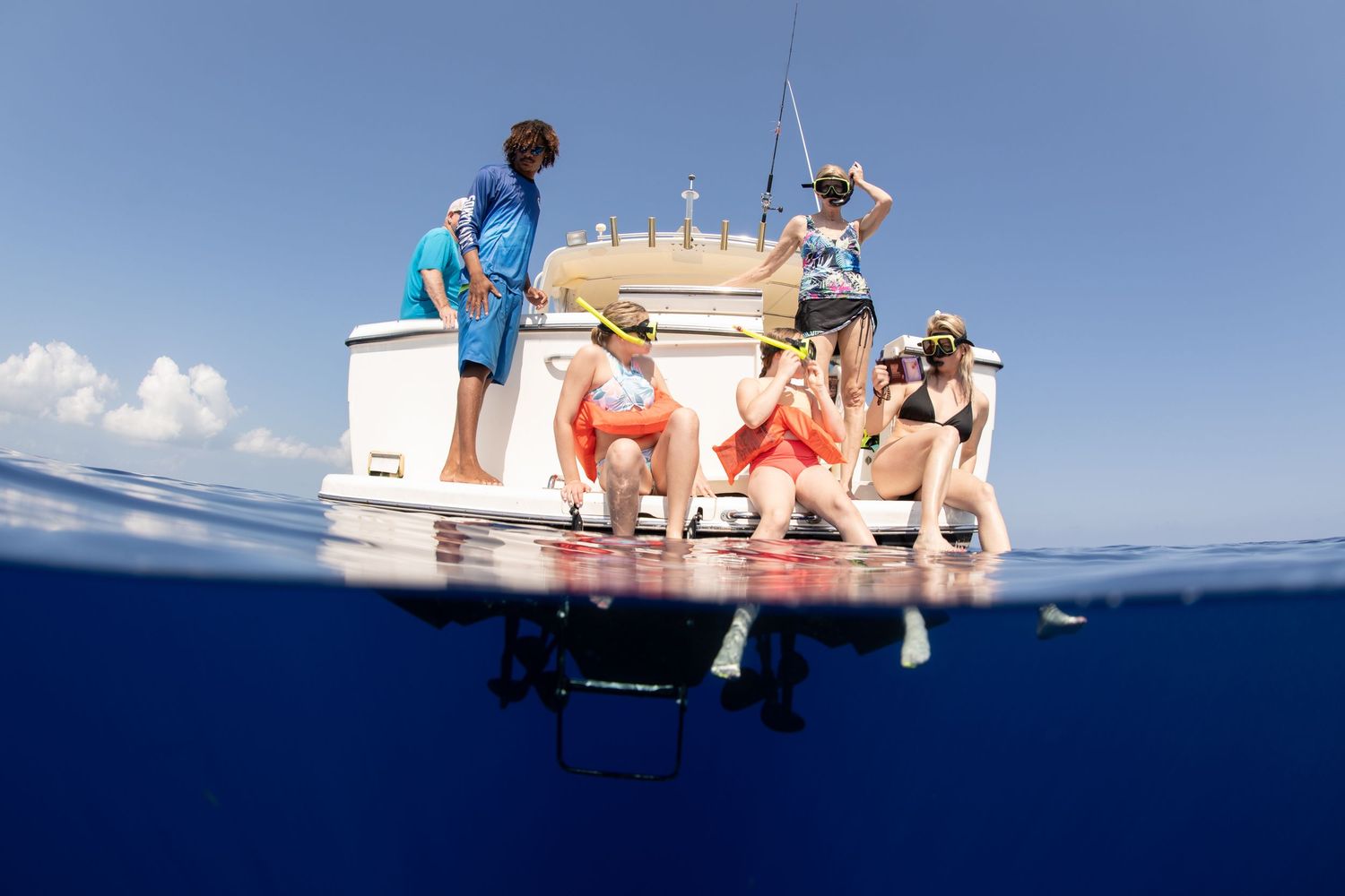 Boats float on calm tropical waters under bright blue skies during a perfect day at sea.