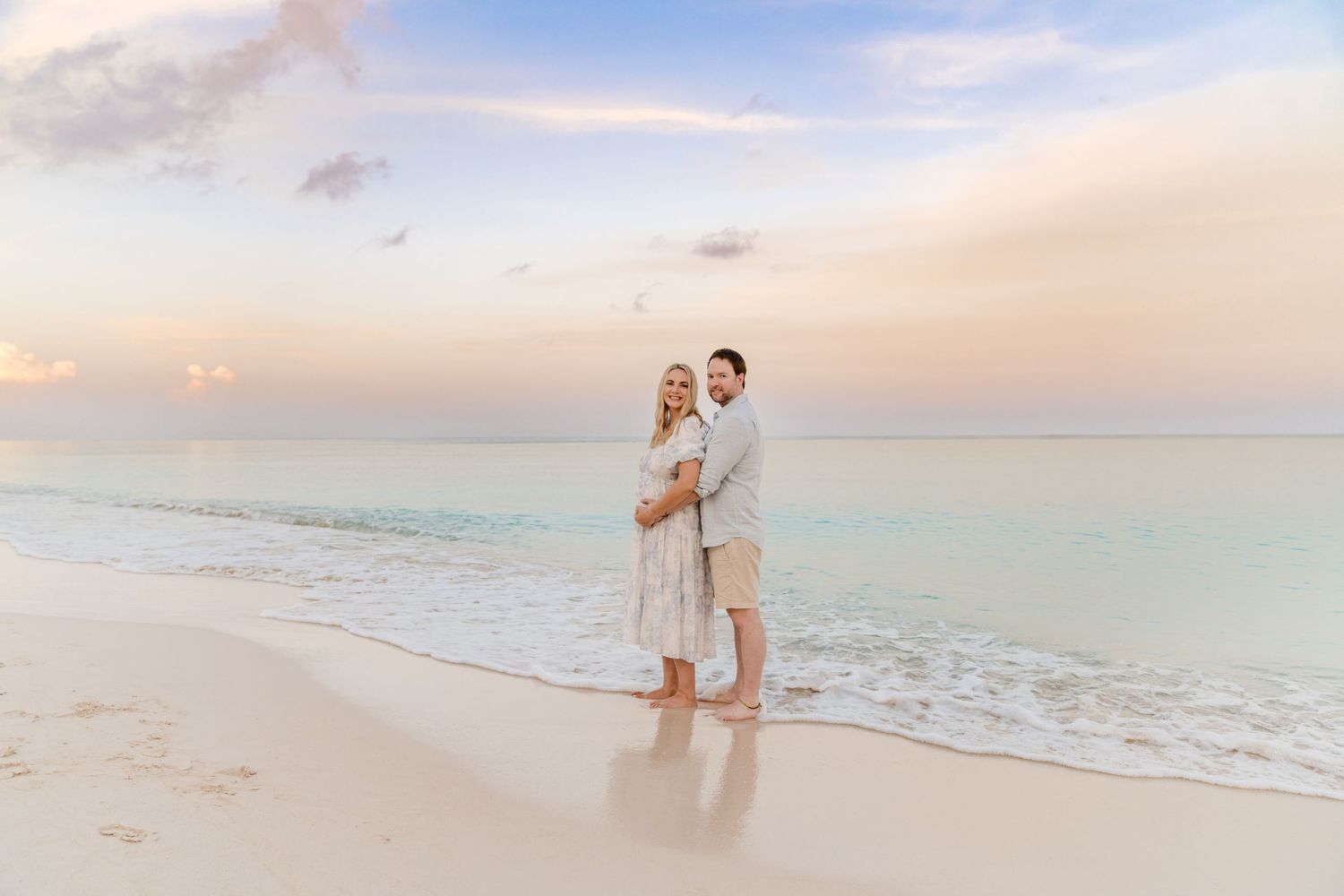 Couple sharing intimate moments on a serene beach at sunset with ultrasound photos.