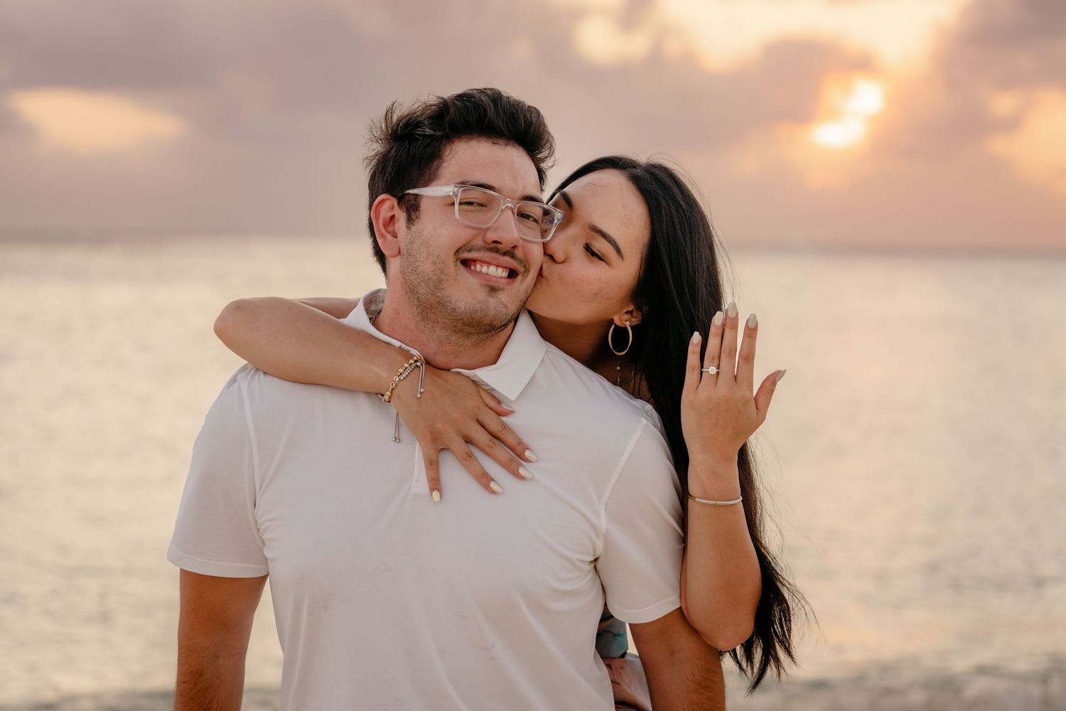 Couple laughing and embracing on a tropical beach at sunset.